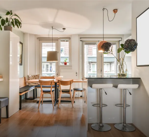 Bright modern kitchen with bar stools and dining table by the window