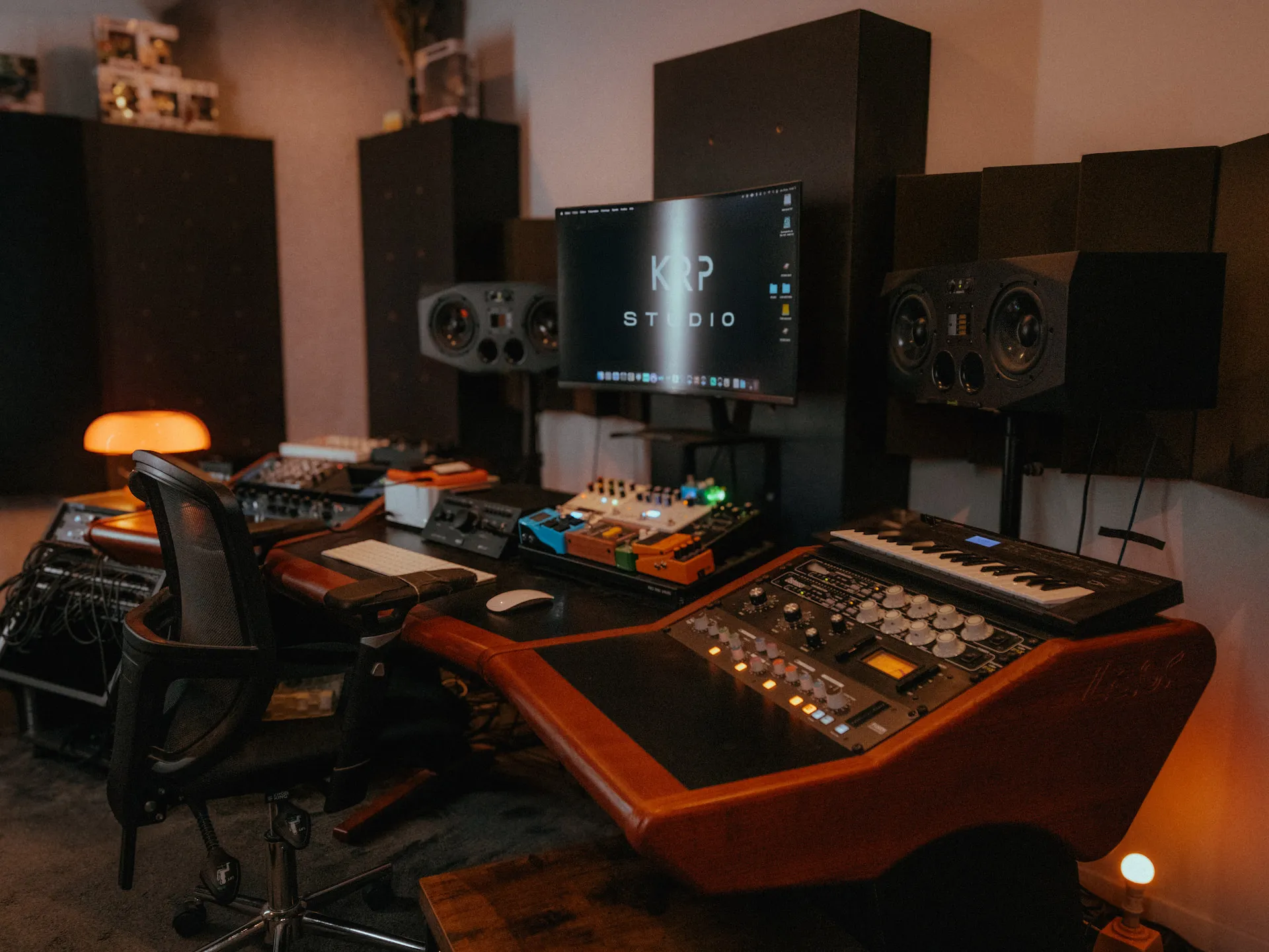 Un rappeur sur scène tenant un microphone, entouré d'un public levant des téléphones portables sous une lumière jaune intense.