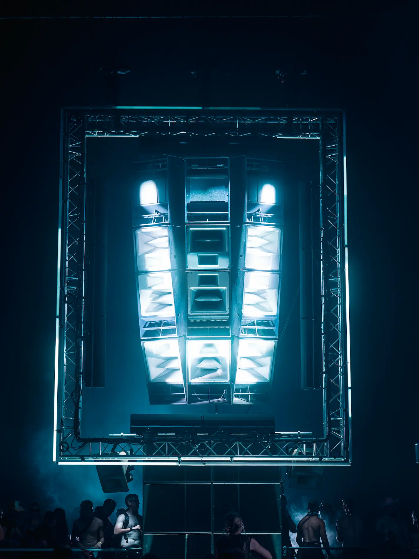 Jeune homme aux yeux bleus avec des cheveux bouclés noirs, portant une veste claire et regardant intensément vers l'avant.