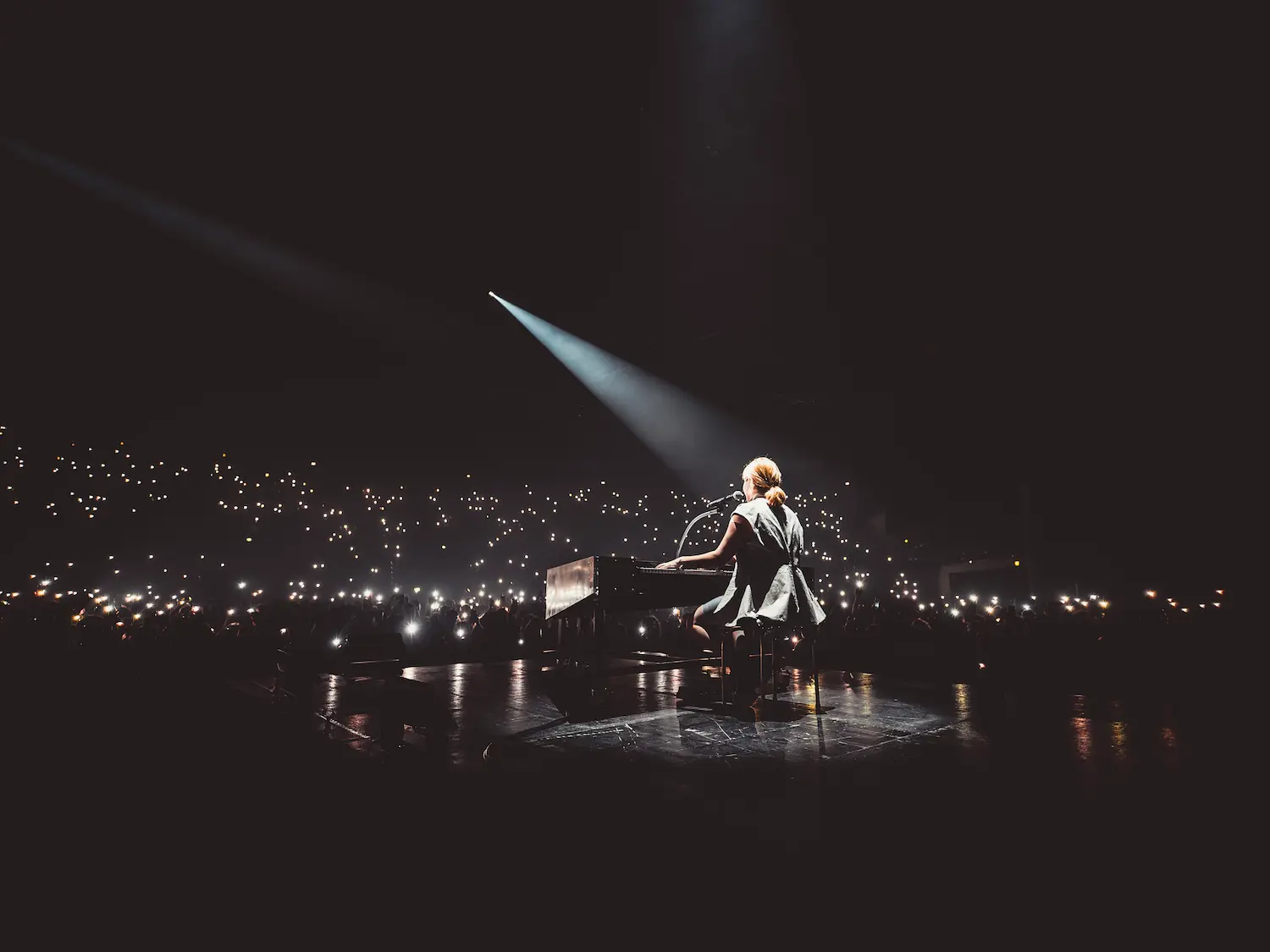 Portrait d'un homme aux cheveux bouclés noirs, à la barbe légère et aux yeux bleus perçants, portant un manteau clair.
