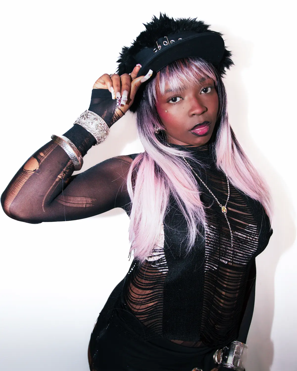 Artiste hip-hop en sweat à capuche et bonnet se produisant sur scène devant une foule avec des téléphones allumés en l'air sous un éclairage jaune vif.