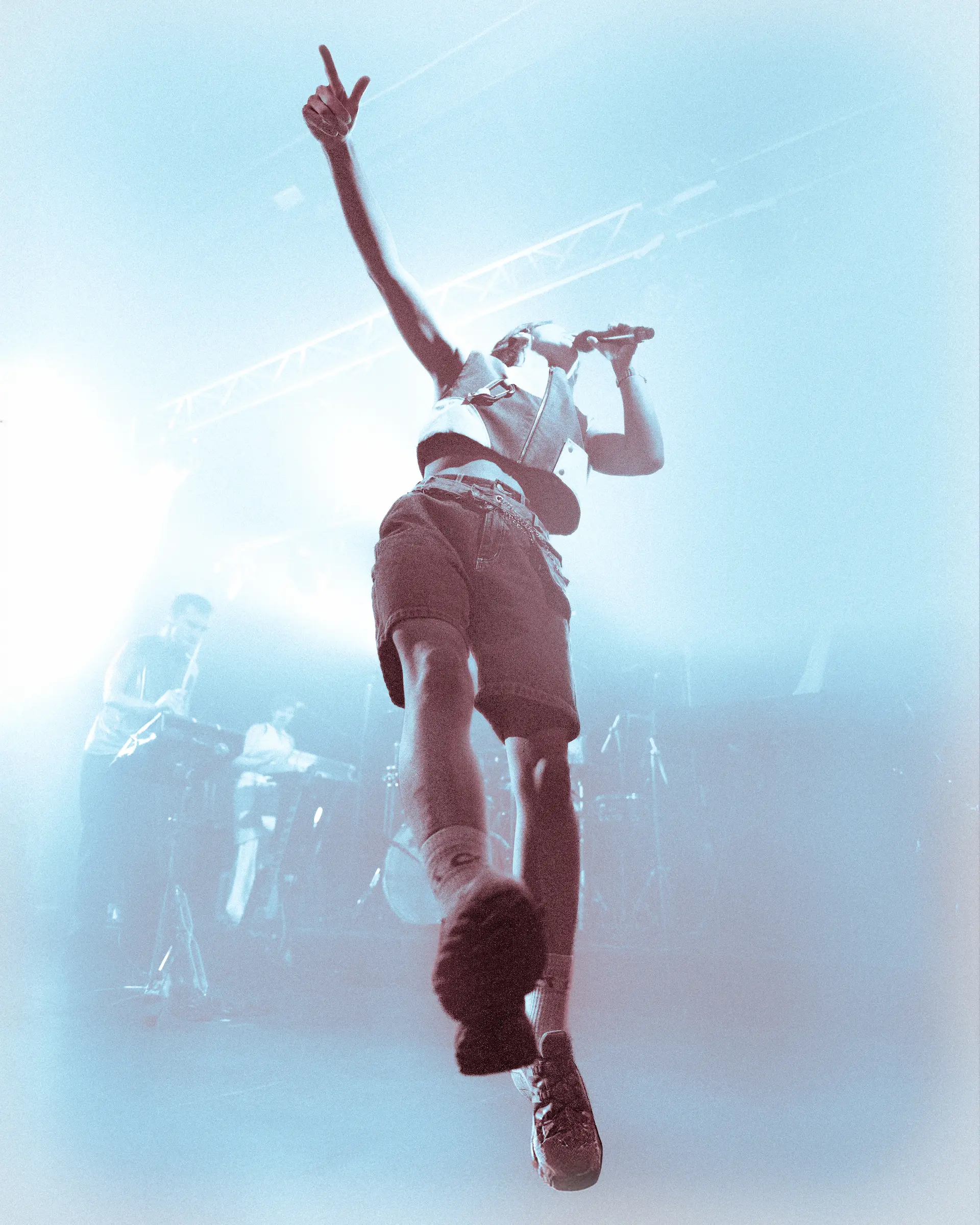 Un artiste hip-hop sur scène avec un micro devant une foule enthousiaste éclairée par une lumière jaune intense.