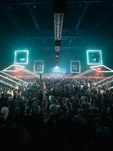 Quatre hommes regardant vers la caméra, photographiés en contre-plongée sous un ciel bleu clair.