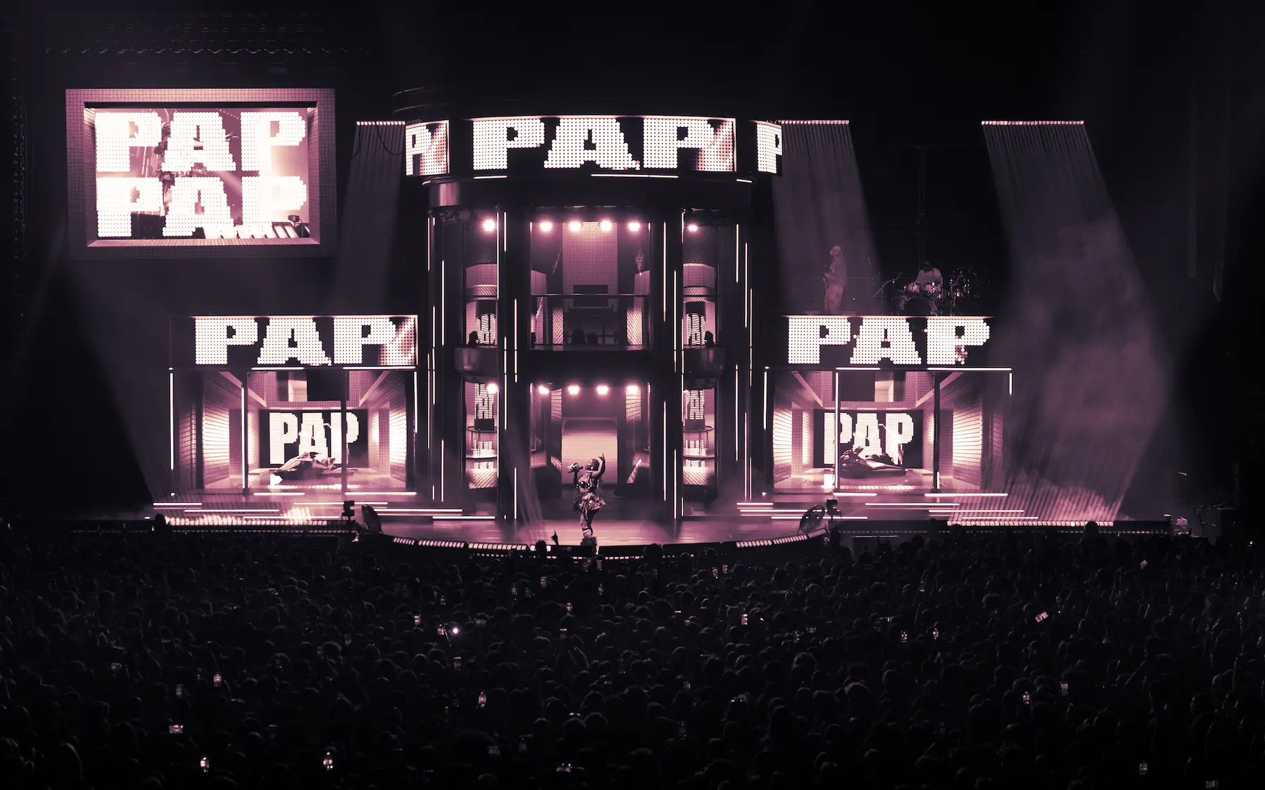 Foule dense et enthousiaste lors d'un concert avec des gens tenant des téléphones portables levés.