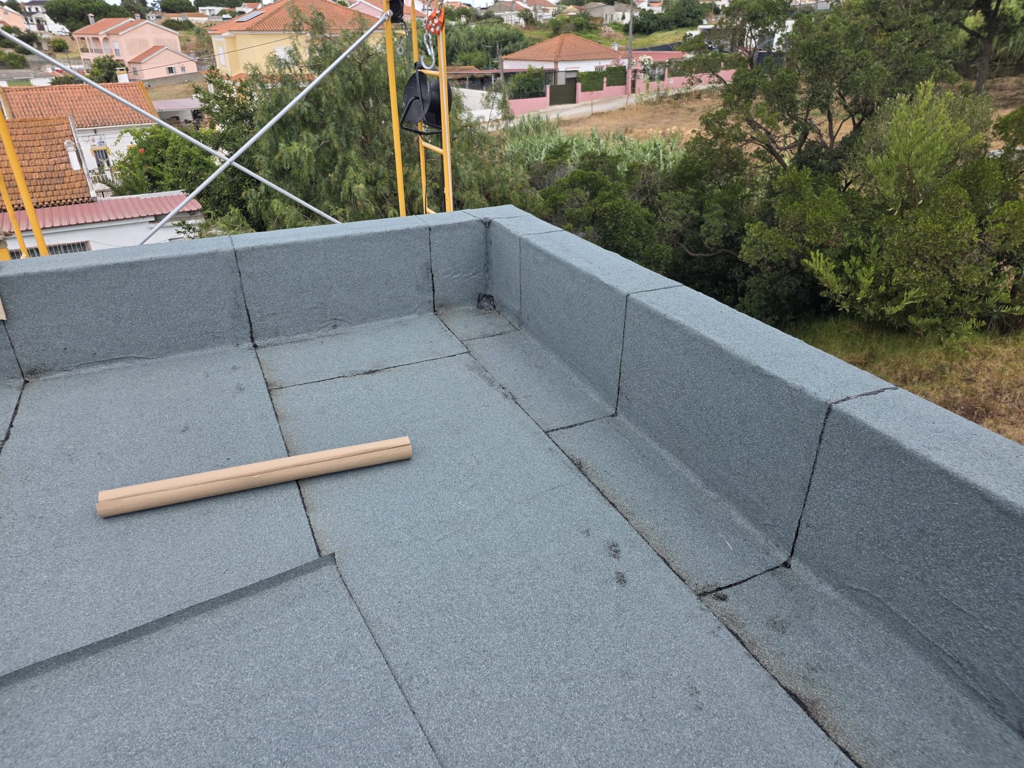 Cobertura impermeabilizada em piso e paredes com material cinzento, com rolo de papel castanho no chão.