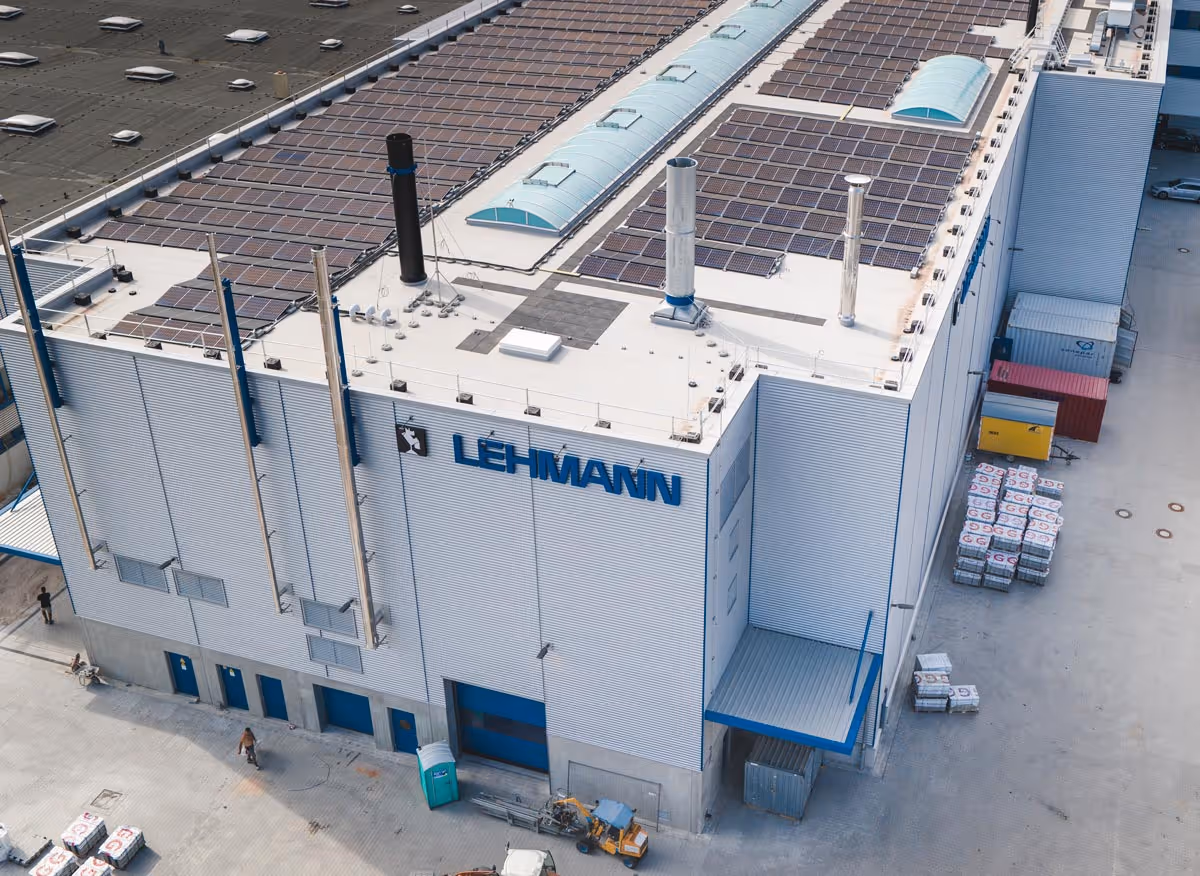 Luftaufnahme eines Industriegebäudes mit dem Schriftzug Lehmann und Solarpanelen auf dem Dach.