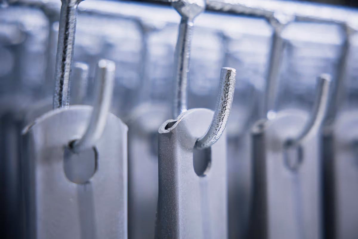 Nahaufnahme von metallischen Haken mit feuerverzinkter Oberfläche, die an einer Stange hängen.