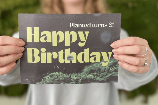 Das Bild zeigt eine Person, die ein Schild mit "Happy Birthday" in die Kamera hält