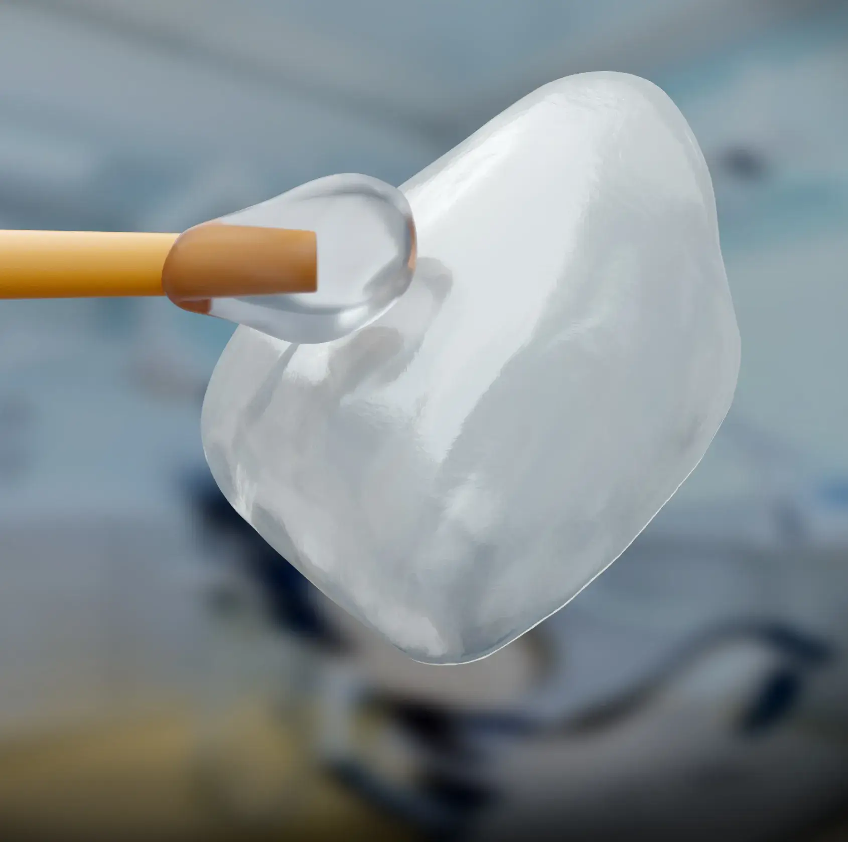 Close-up of a dental veneer being held by tweezers, in front of a blurred background.