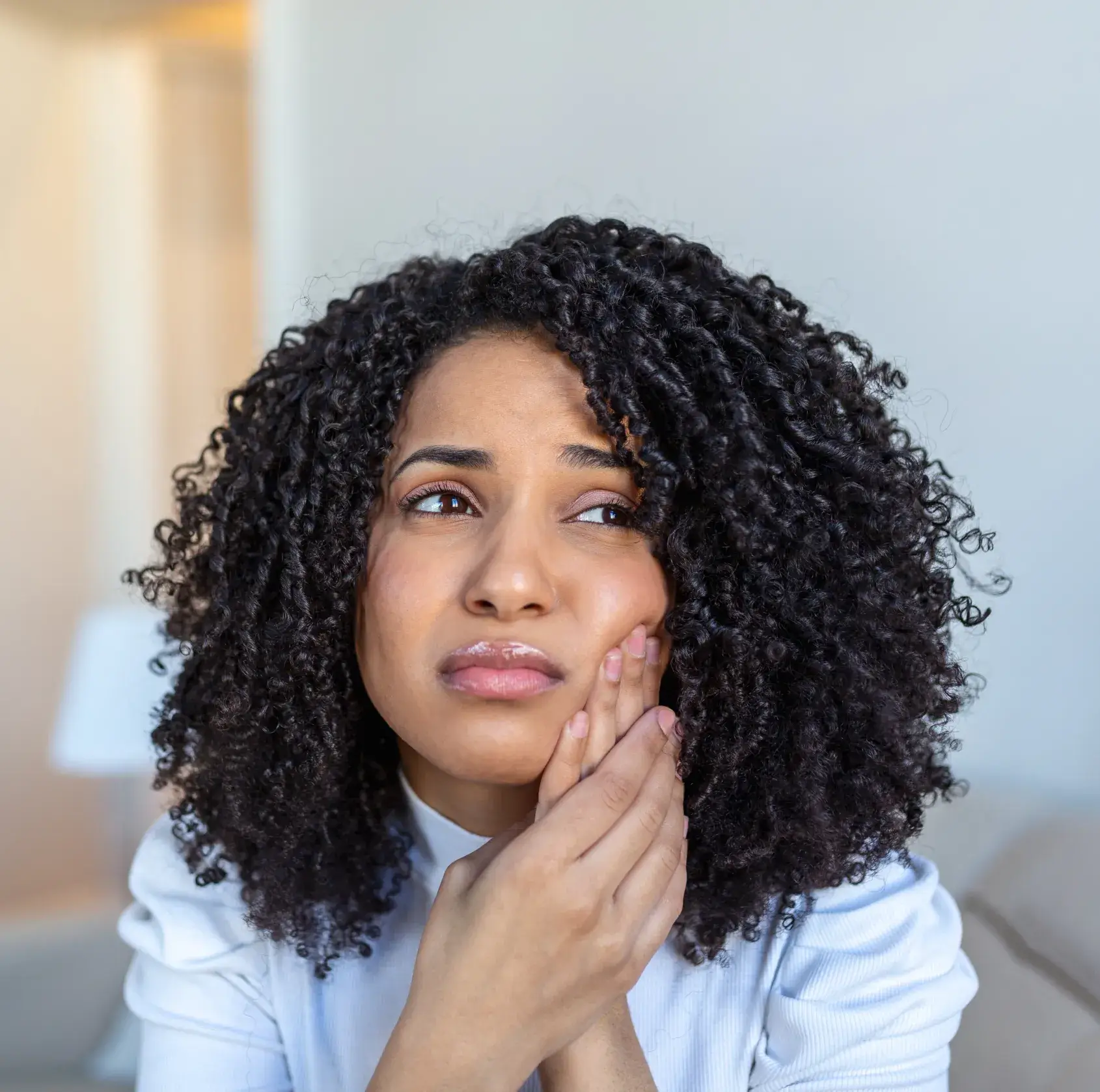 A woman holds her cheek, appearing to have a toothache.