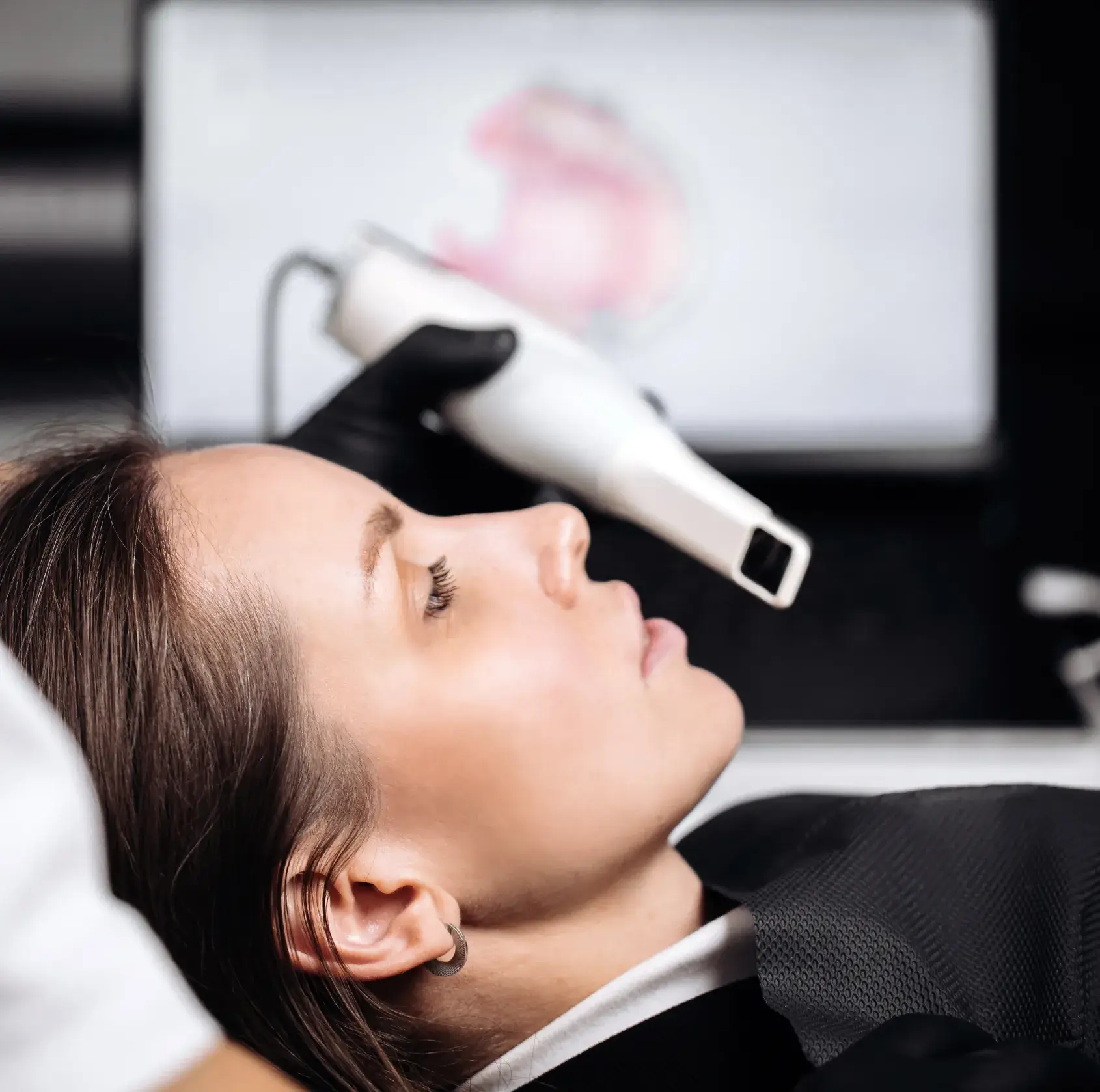 A person is receiving a non-invasive facial treatment with a handheld device on their forehead.
