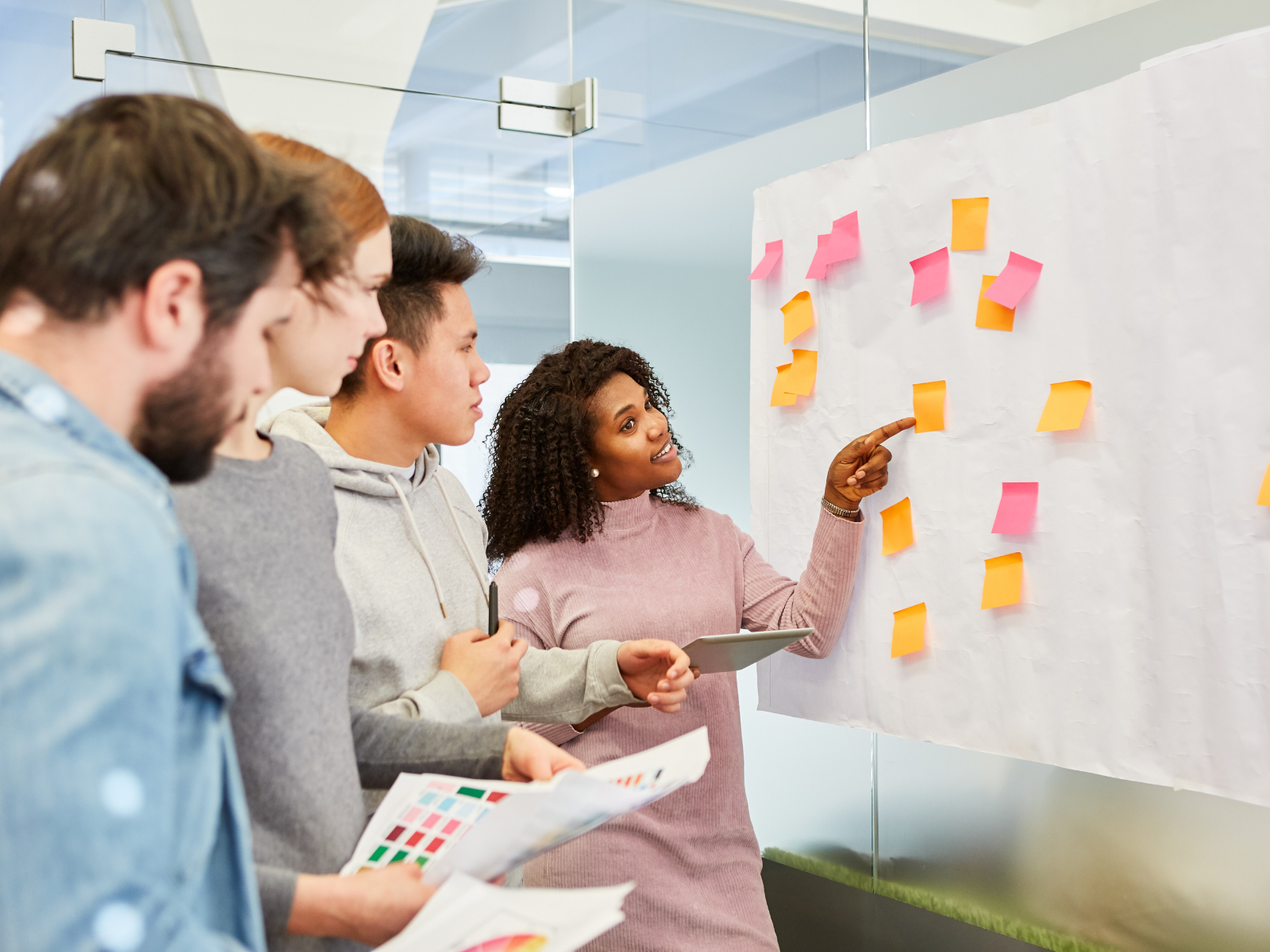 a group of people looking at a white board with sticky notes