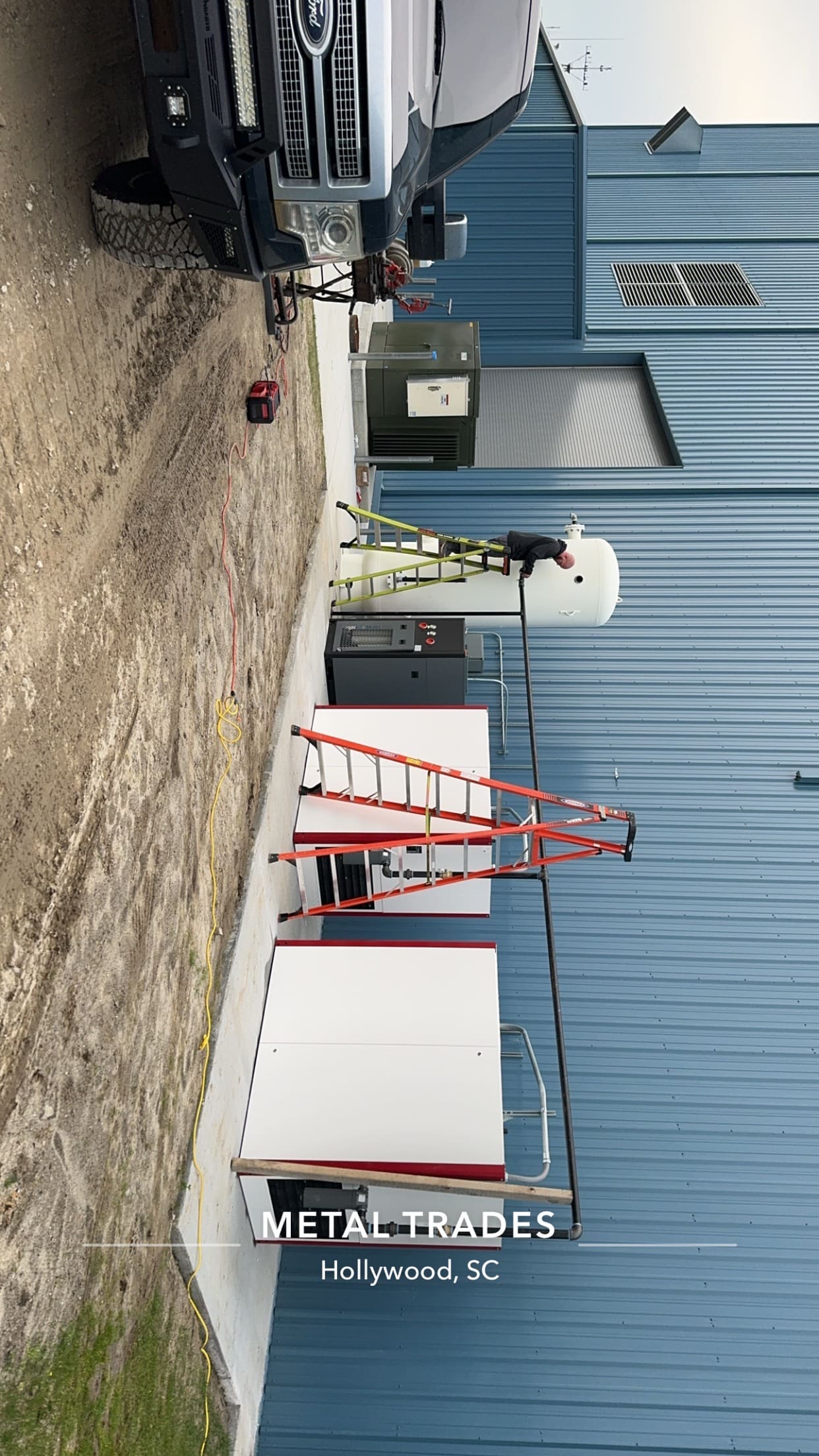Full air system being installed by a BM Industrial Solutions contractor outside a commercial building next to a black Ford truck with "Metal Trades Hollywood, SC" text overlay on the image