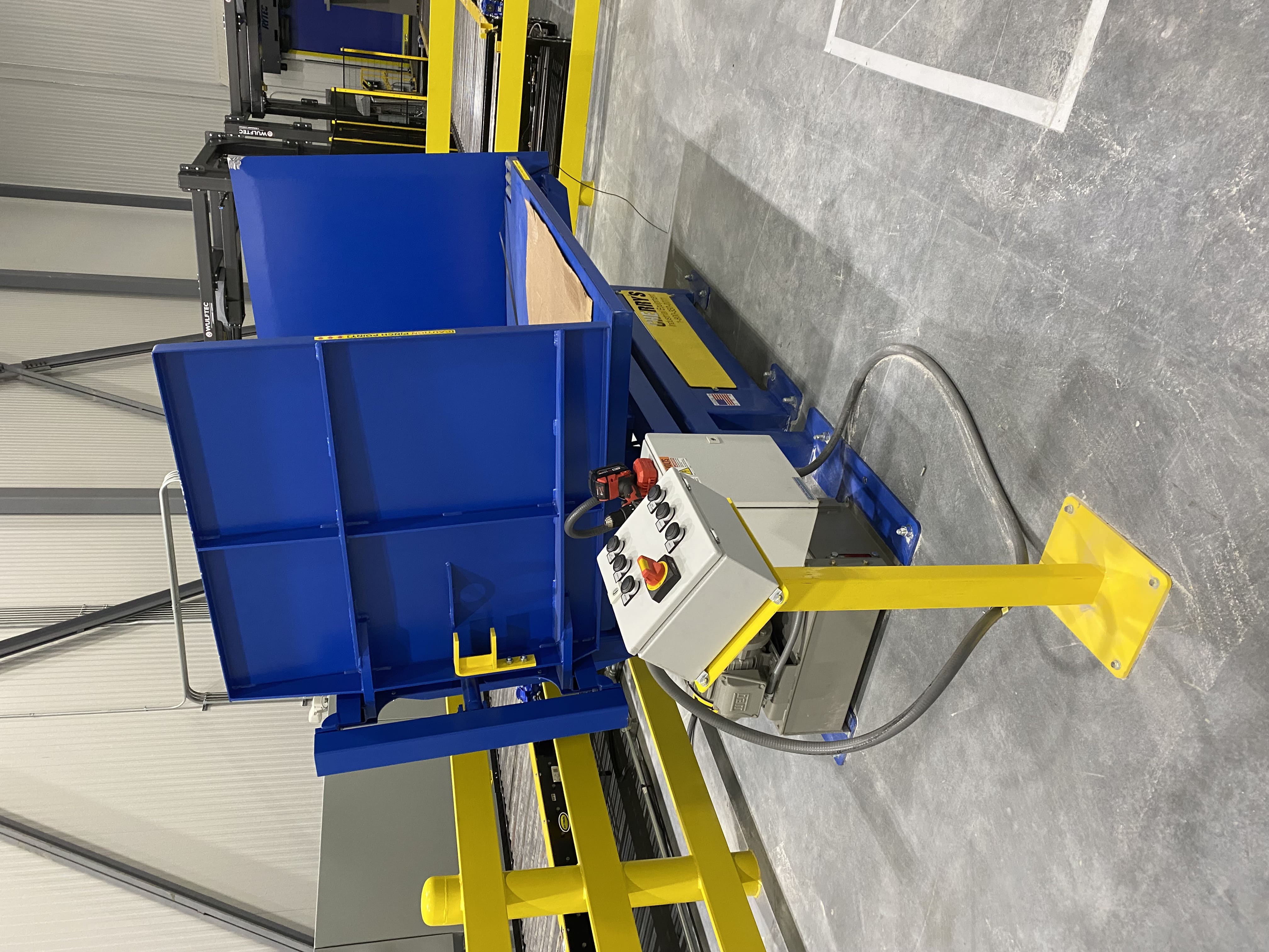 blue industrial mechanical machine on a concrete platform with yellow rails