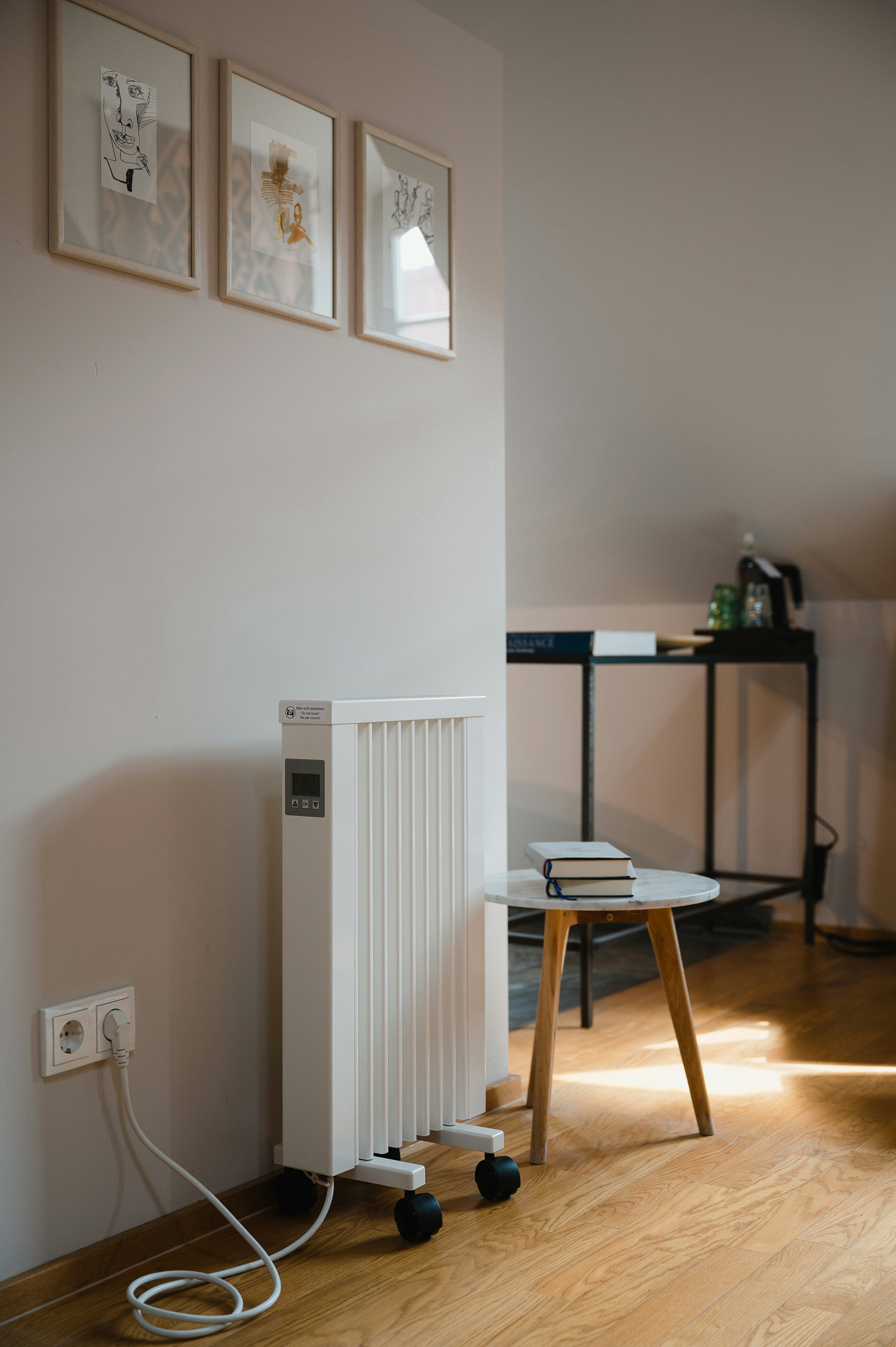 Minimalist room with electric heater, side table, books, and framed artwork