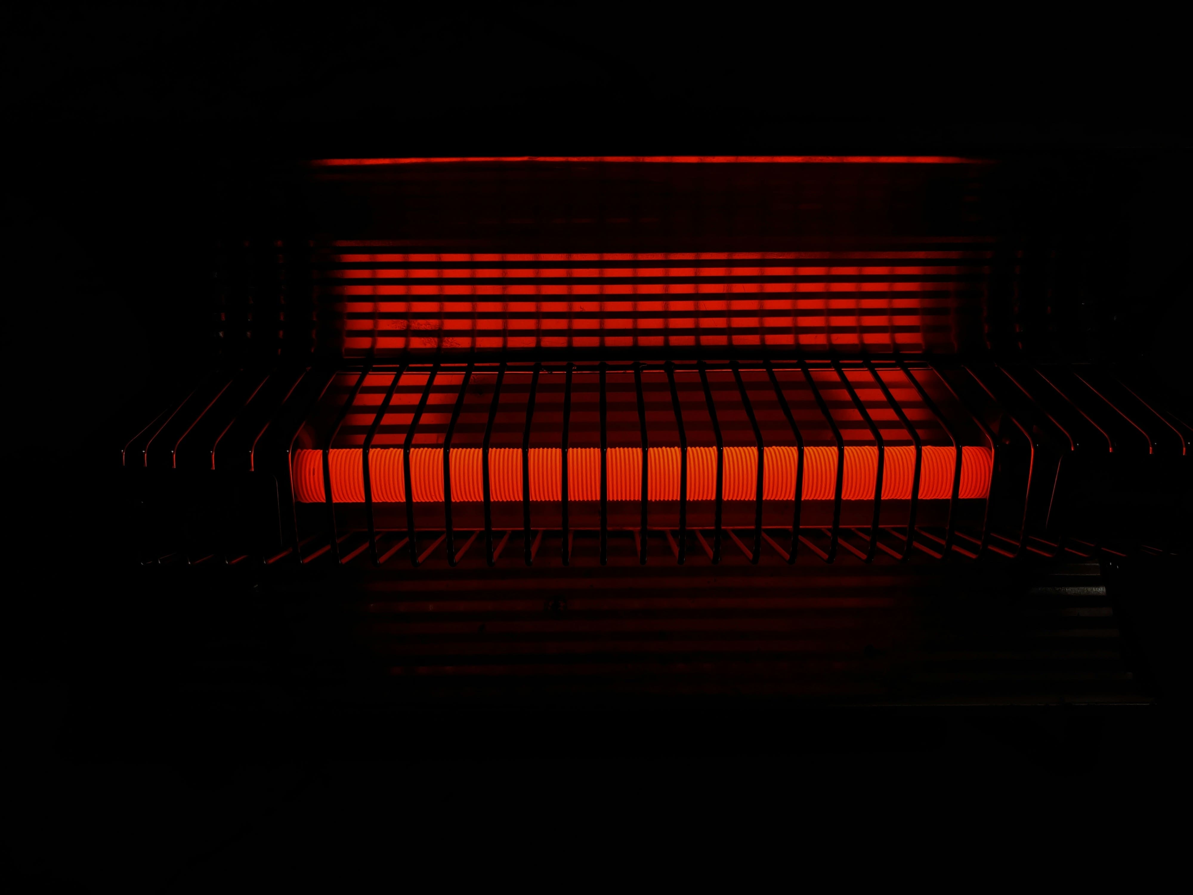 Glowing red electric heater with grid pattern in dark background