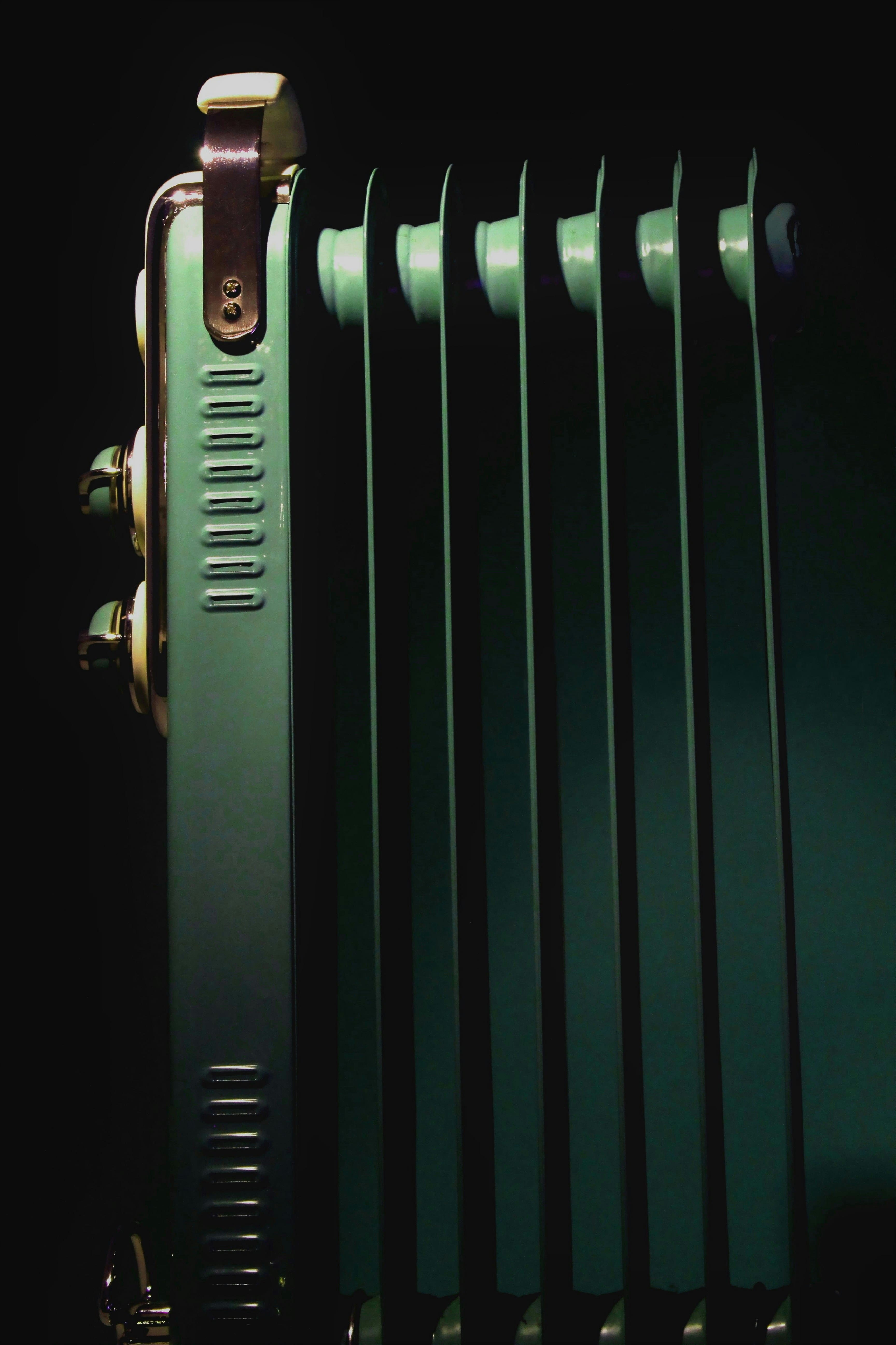 Vintage green oil-filled radiator heater against dark background