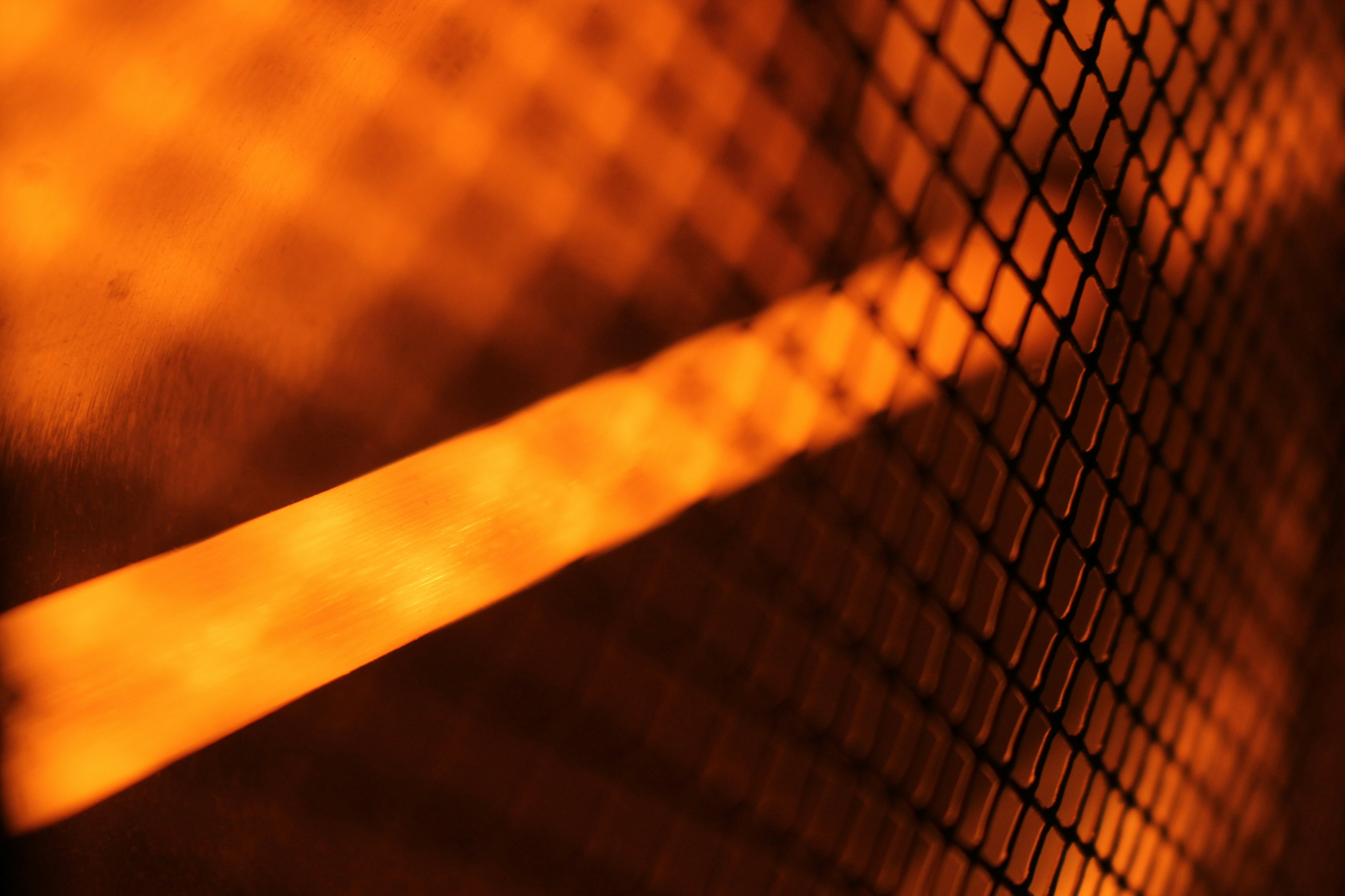 Glowing orange beam of light casting shadows through wire mesh fence