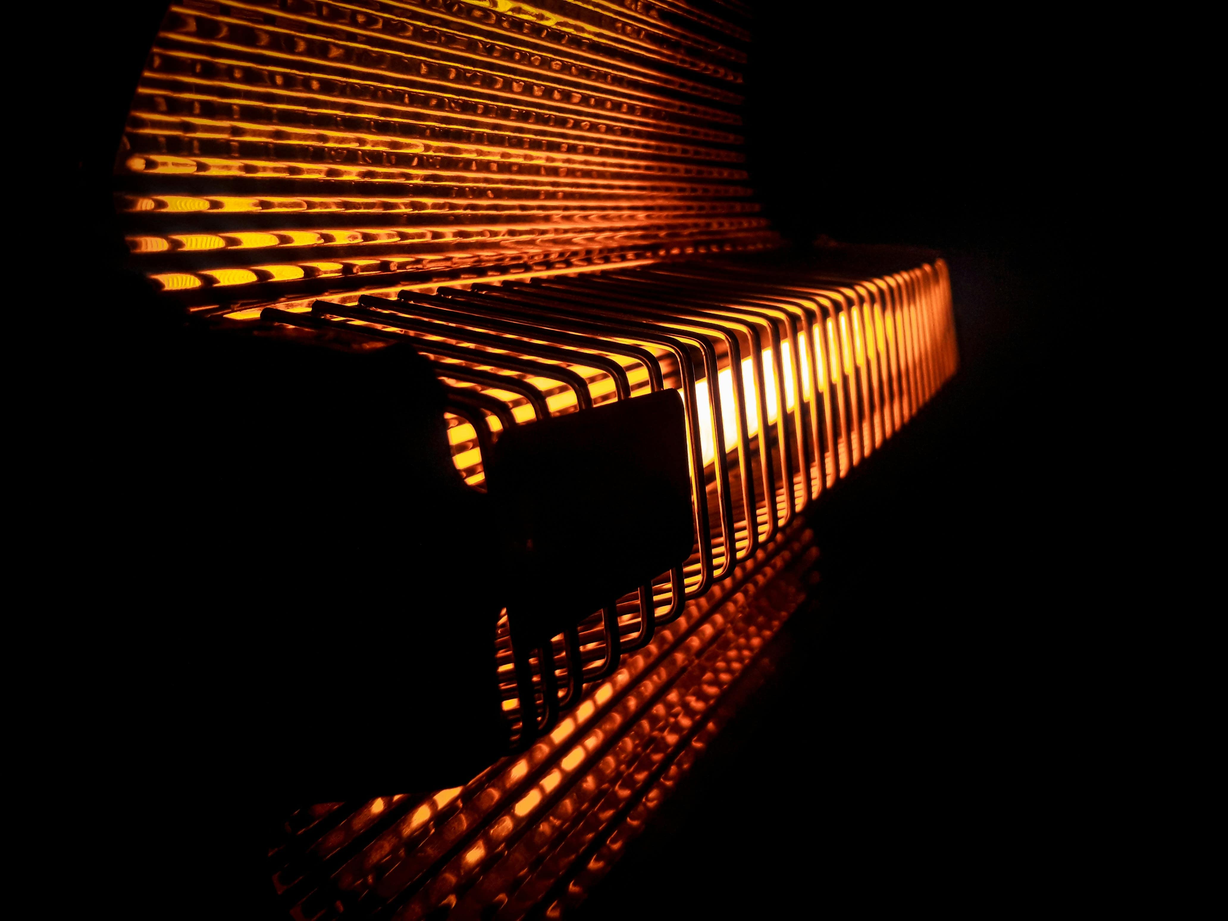 Glowing orange metal grid structure curving in dramatic light pattern