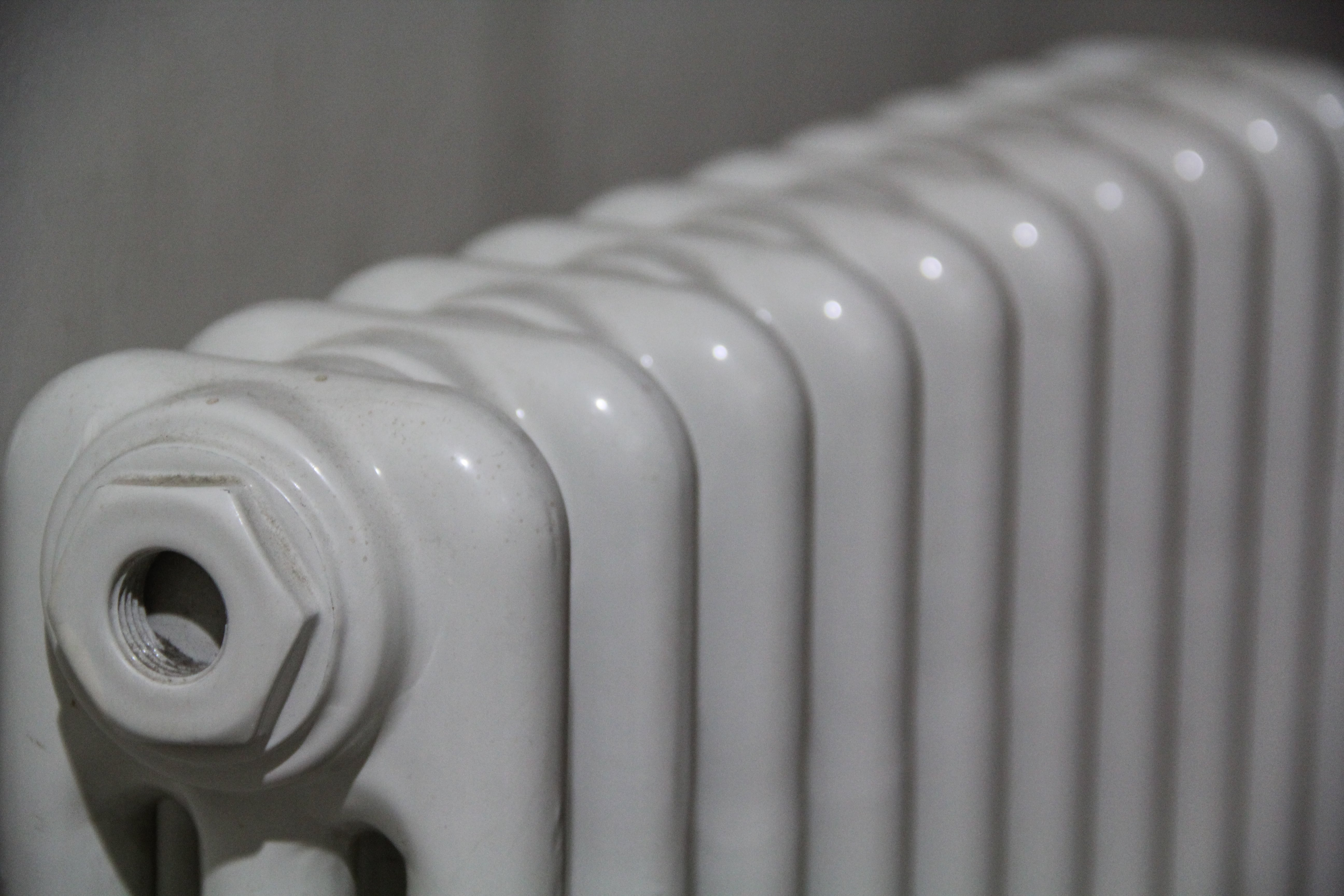 White vintage radiator with multiple ribbed sections and central valve