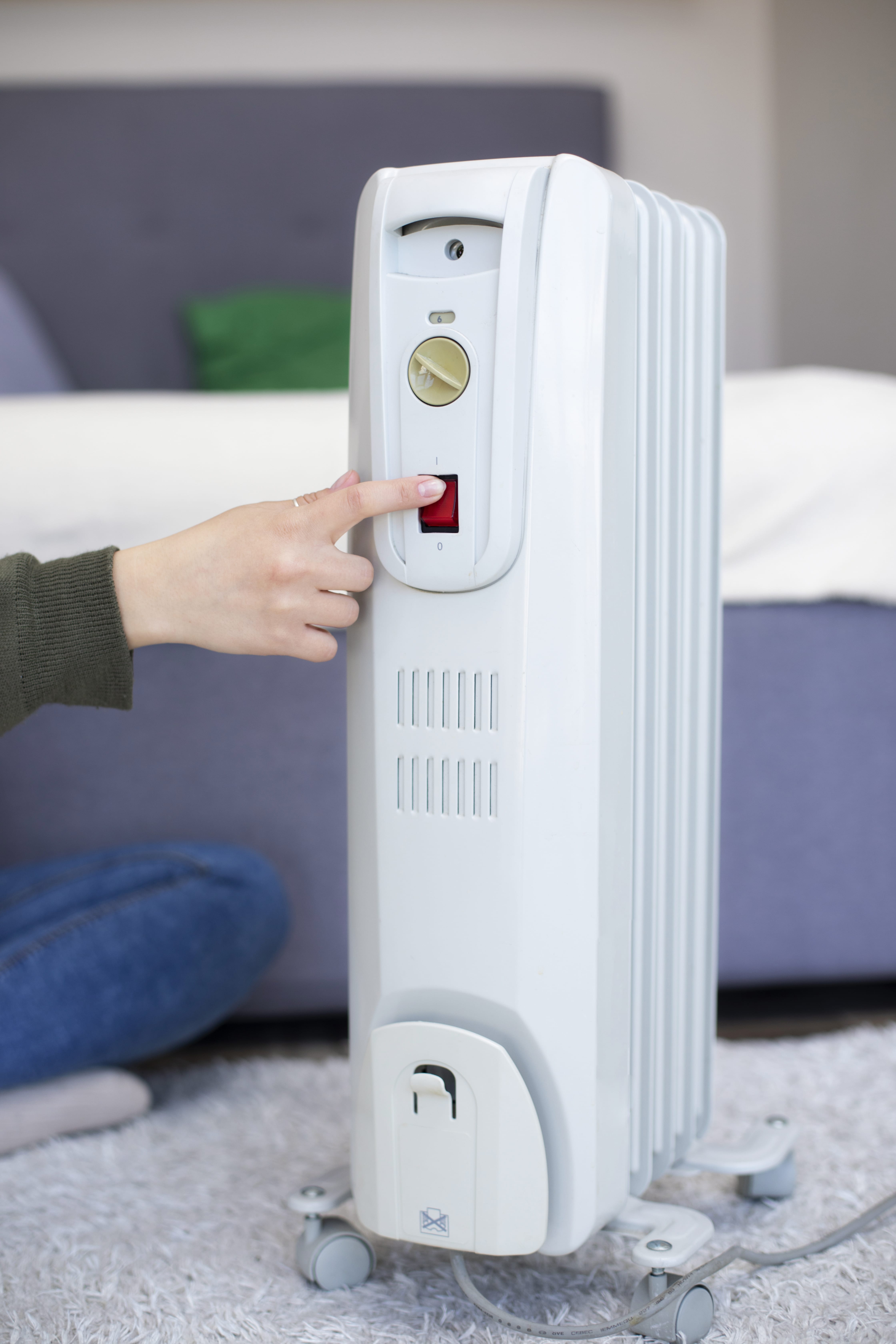White oil-filled radiator heater with hand turning on red power switch