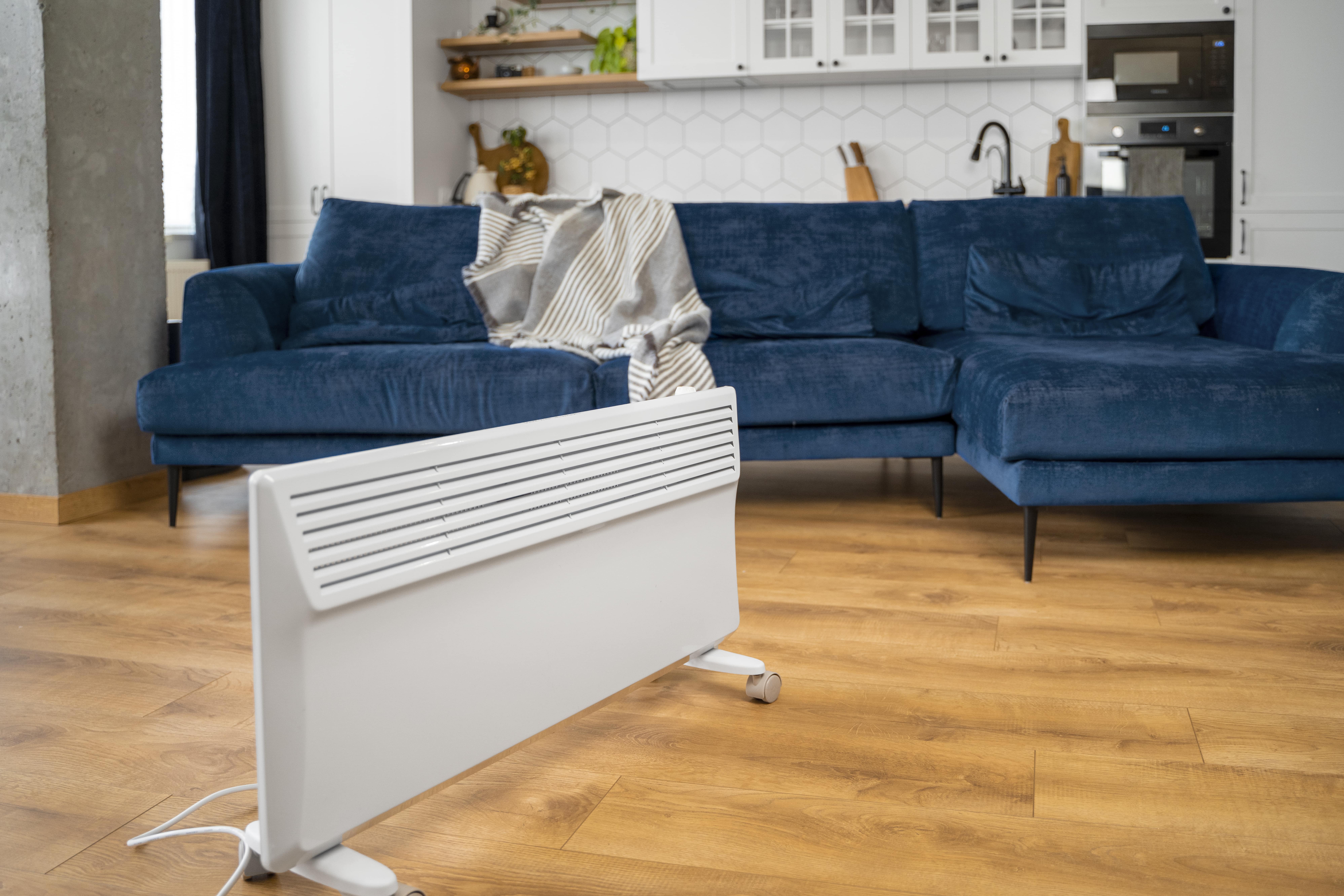 White electric heater near blue sectional sofa in modern kitchen