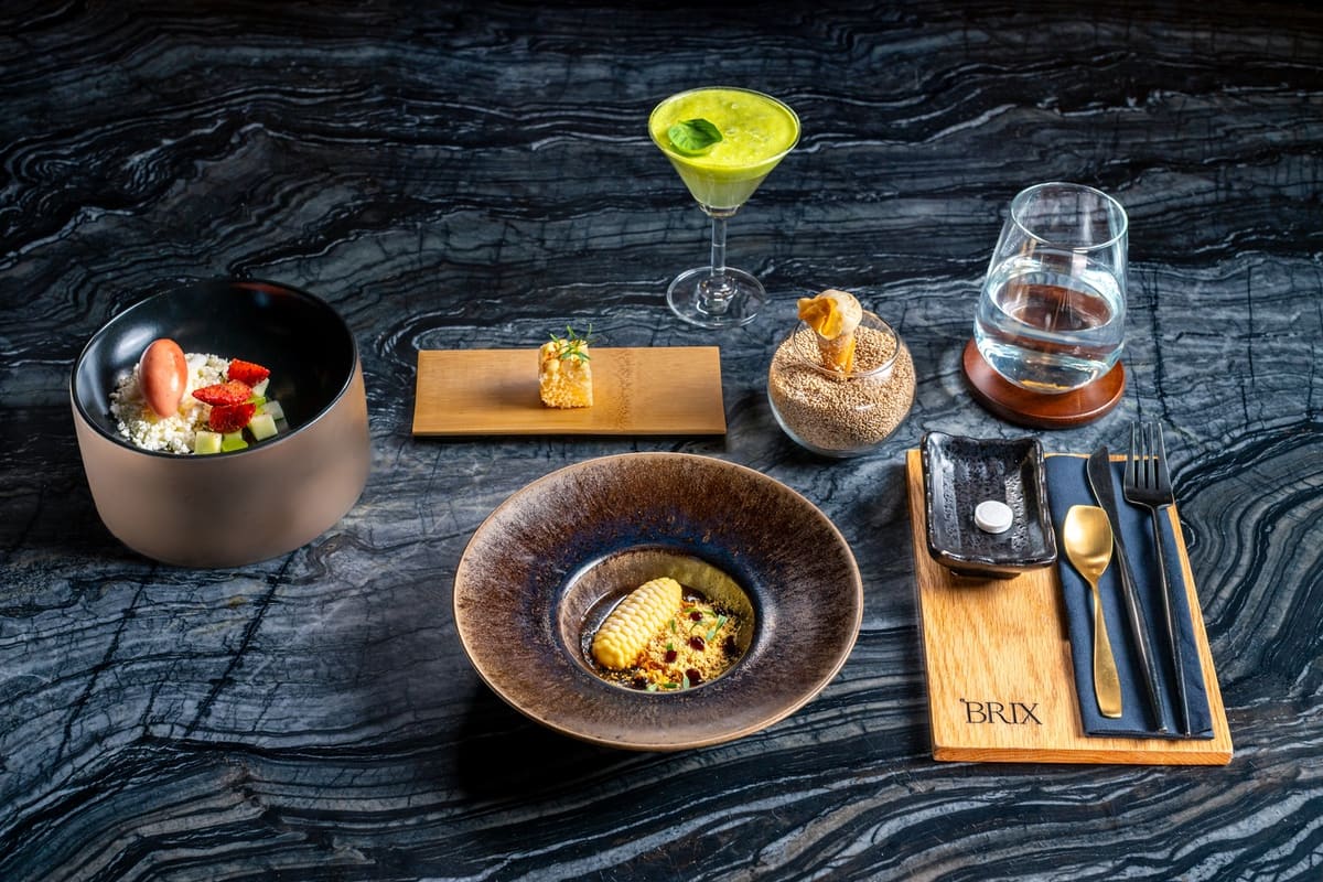 Gourmet tasting menu with five distinct dishes and a glass of water on a dark marble table at BRIX restaurant.
