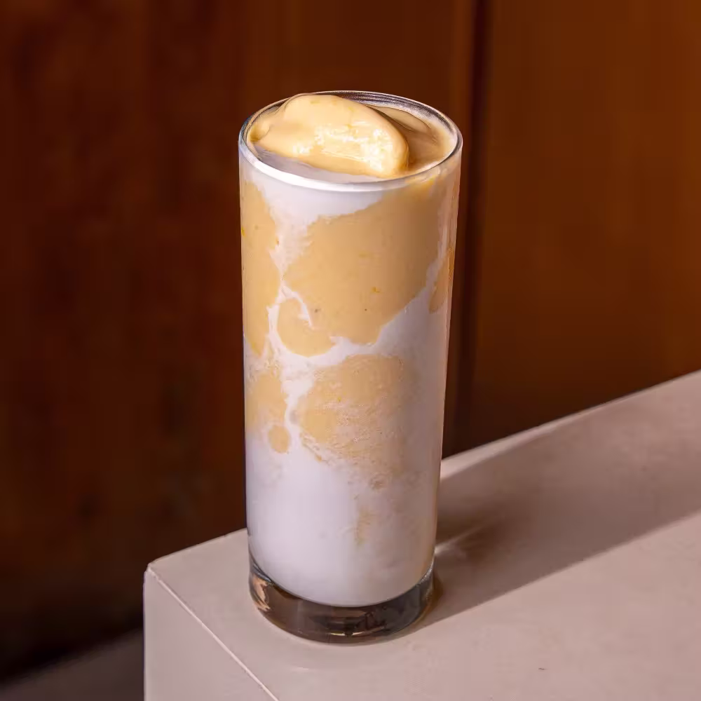 Golden Protein Shake with swirls of mango and sweet melon in a tall glass - Brix Cafe Dubai