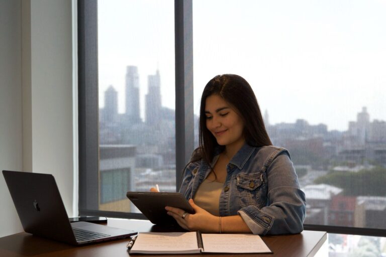 Woman writing in notebook with city skyline behind – guiding expert brands to build scalable digital businesses with intention