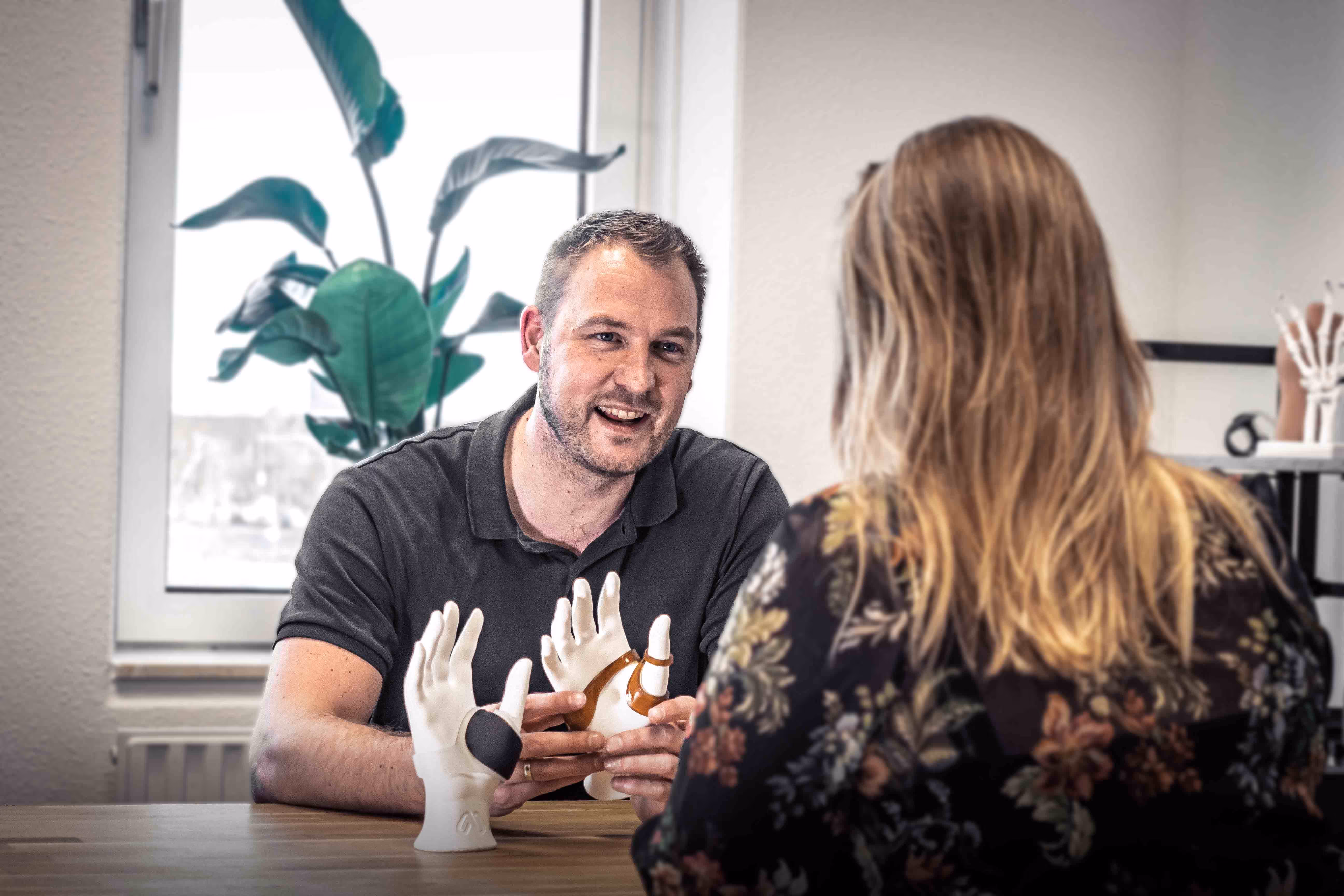 Manometric employee discussing a hand orthosis brace with a client in the office.