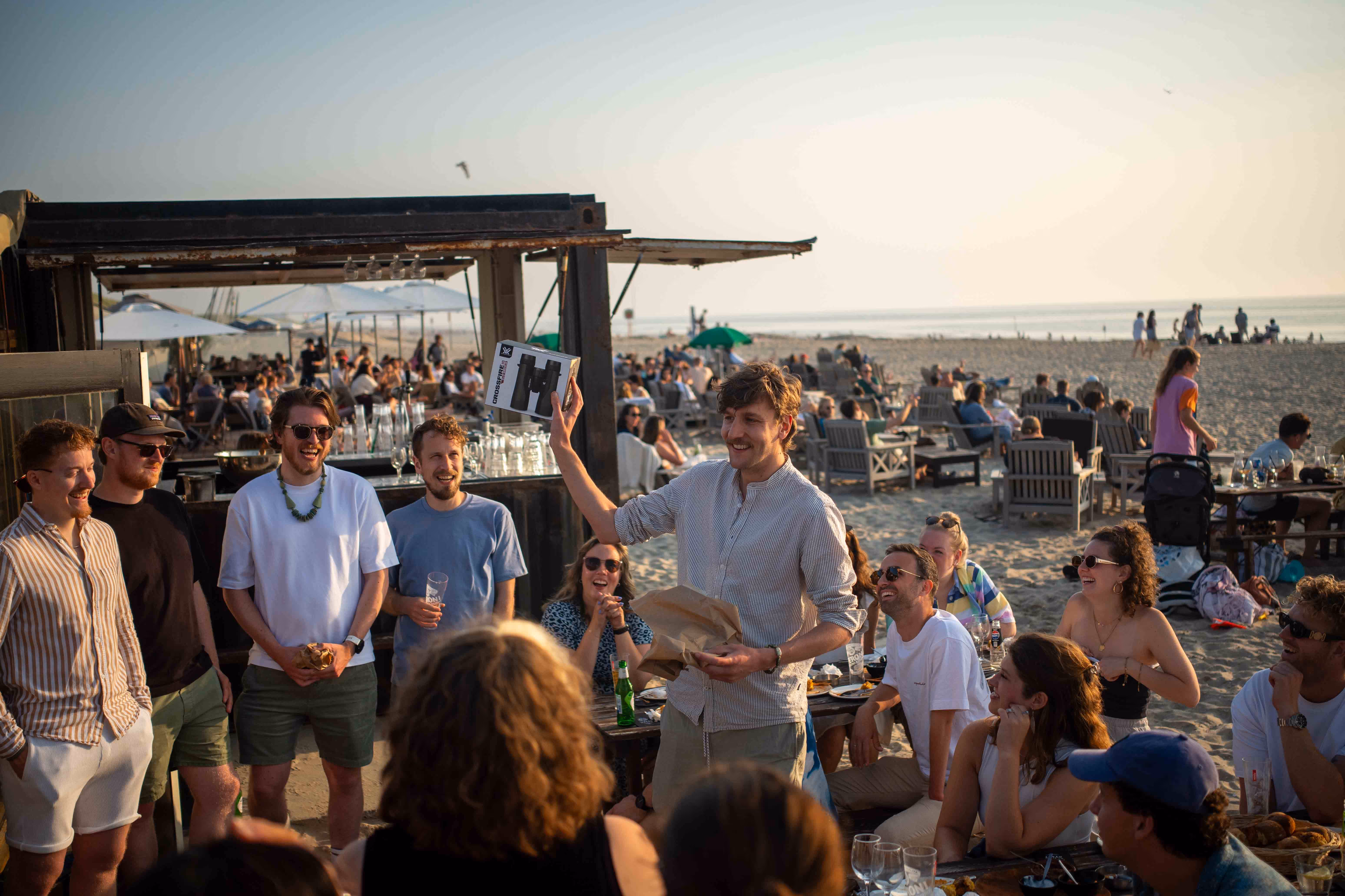 Manometric employees celebrating at a summer beach party, with a team member presenting a prize to colleagues