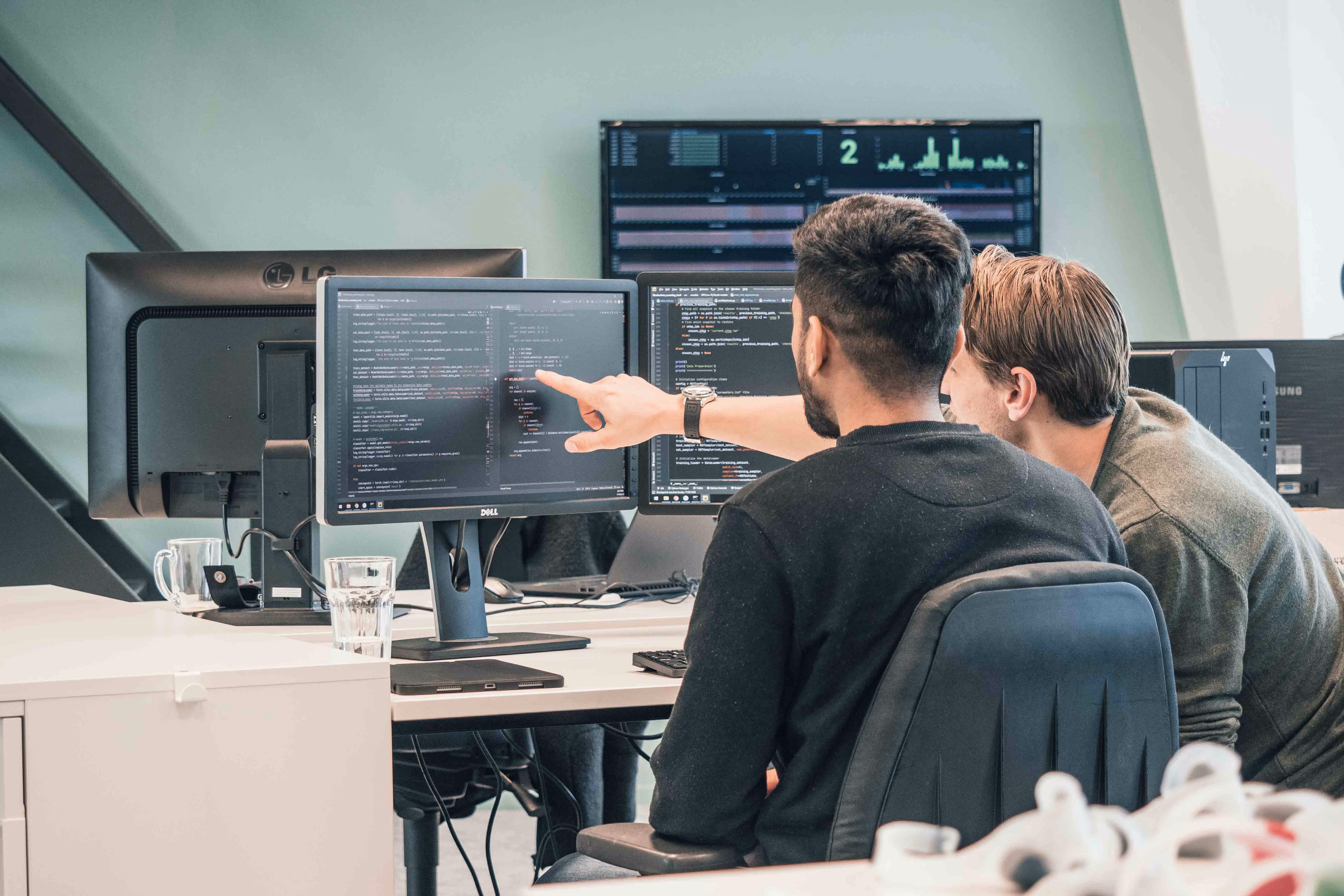 Mitarbeiter von Manometric, die an einem Computerarbeitsplatz an der Softwareentwicklung zusammenarbeiten.