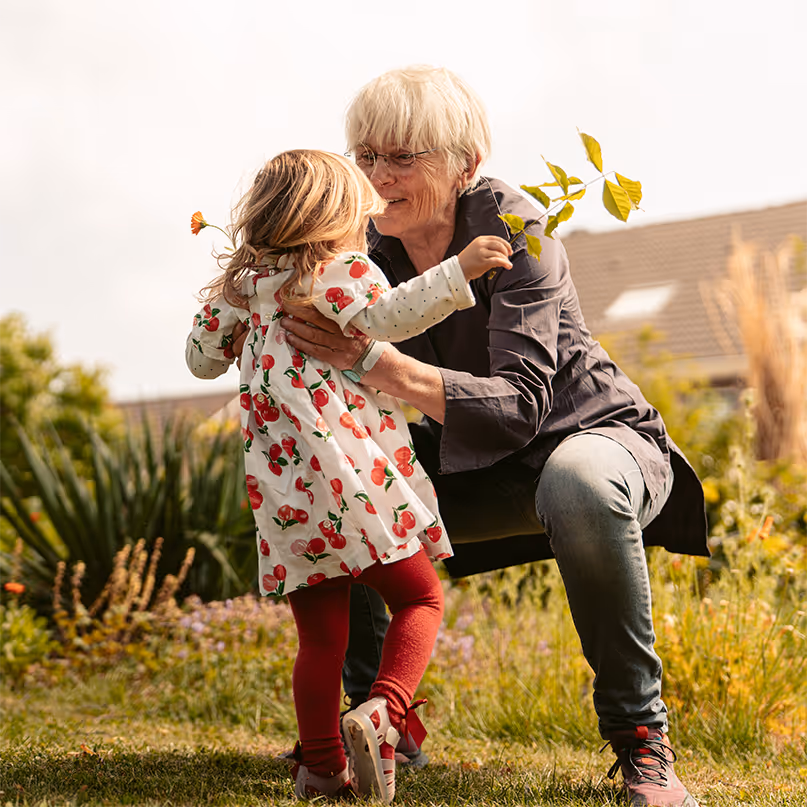 Elderly woman wearing a Mano Air hand brace embracing her granddaughter in a garden.