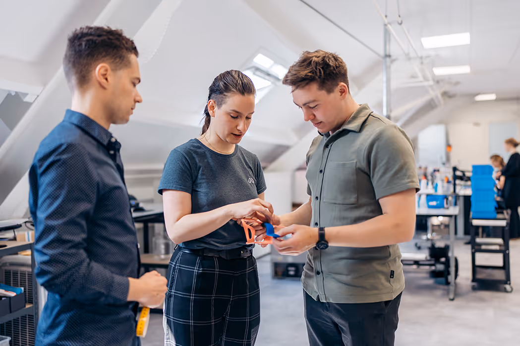 Manometric employees examining and discussing a hand brace prototype in the office.