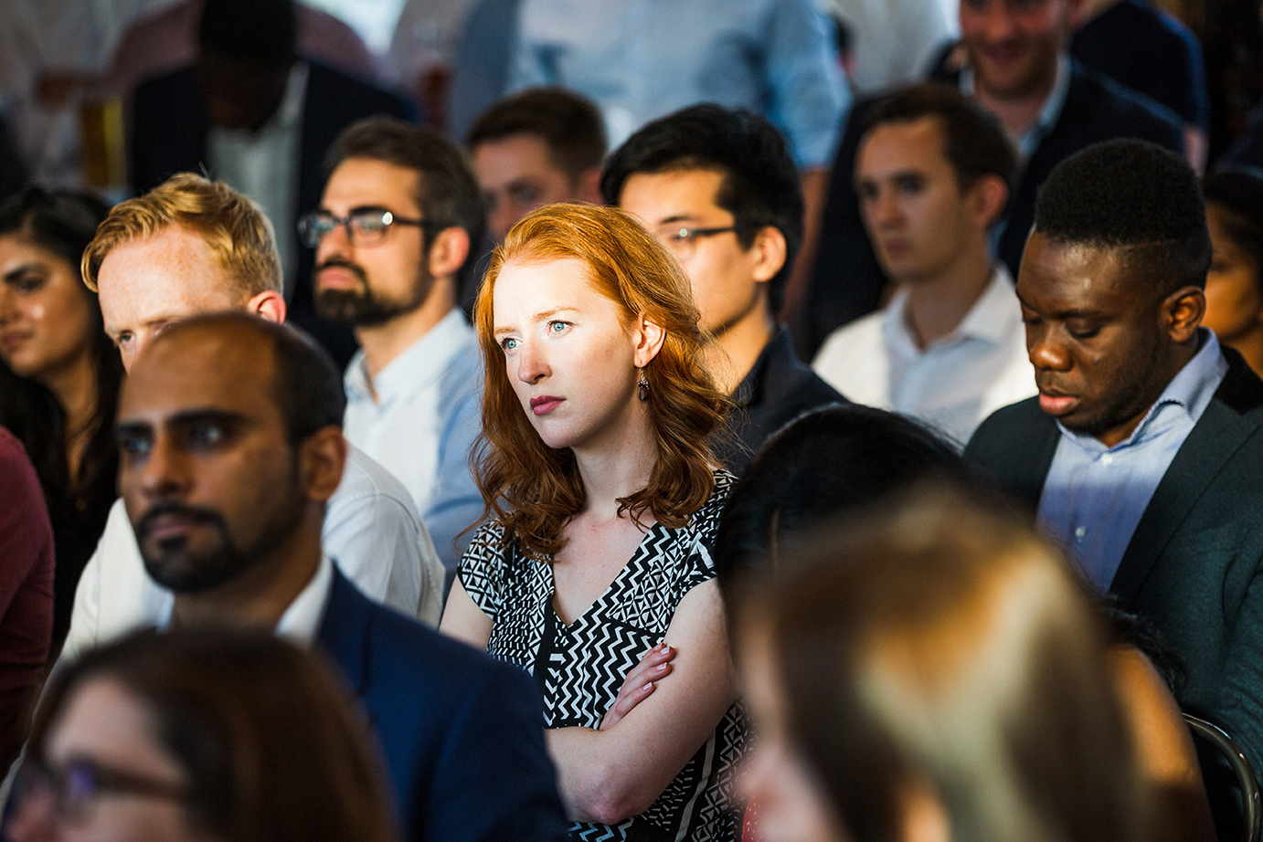 A red-haired woman sitting in a crowd.