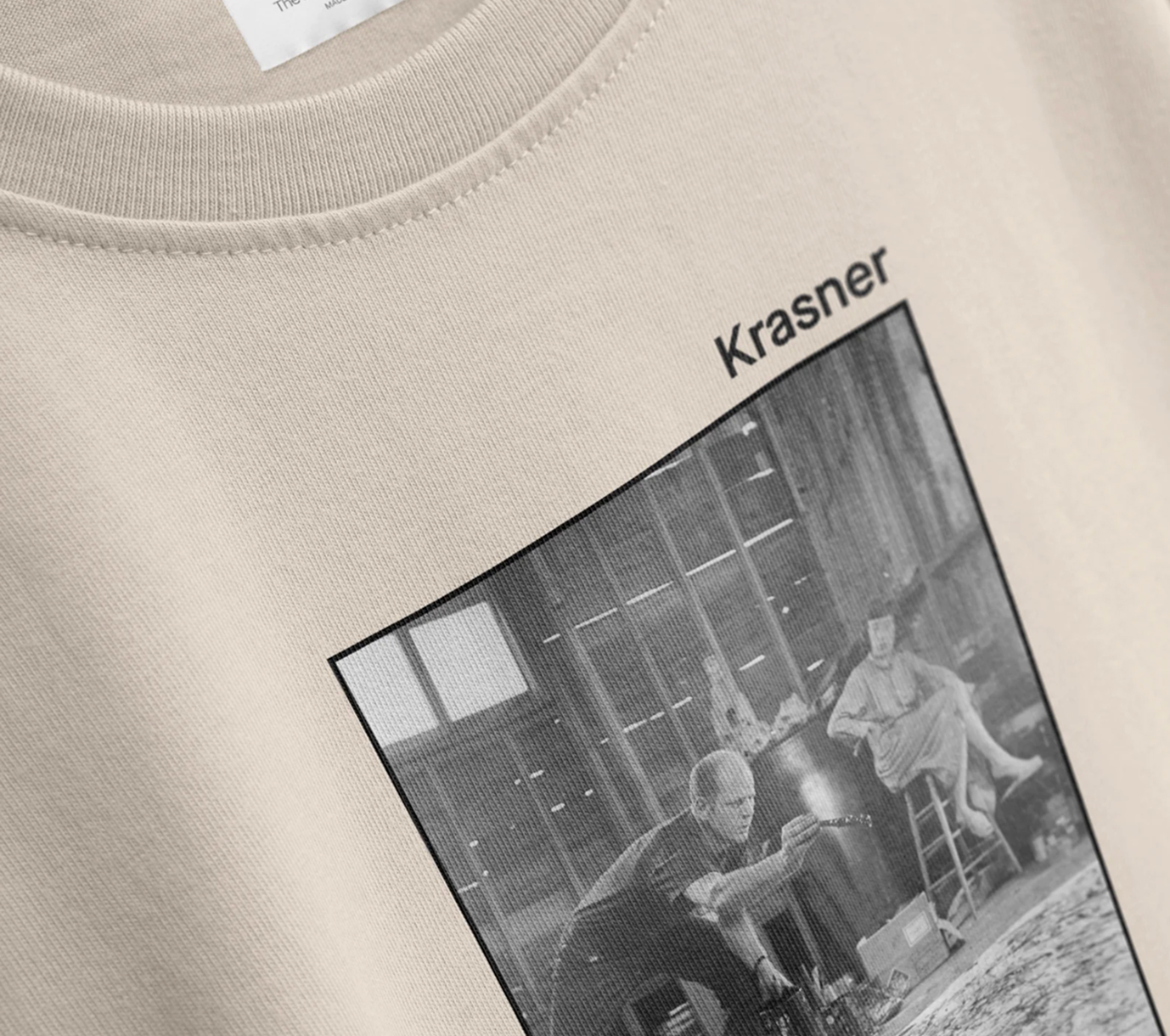 Beige fabric shirt featuring a black and white photo of an artist working on a canvas with another person sitting on a stool, labeled 'Krasner'.