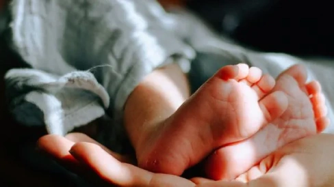 Parents holding their newborn’s feet, symbolizing healthy family planning”