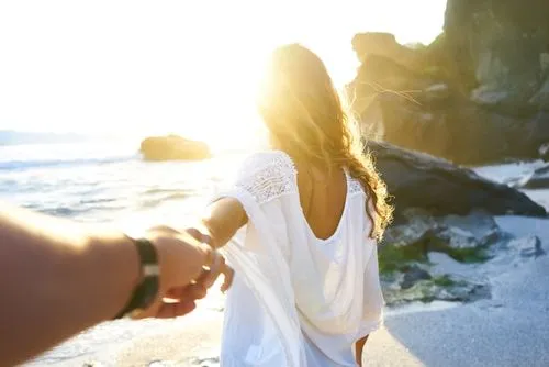 Woman walking forward on the beach while holding someone’s hand, symbolizing empowerment in navigating genetic testing