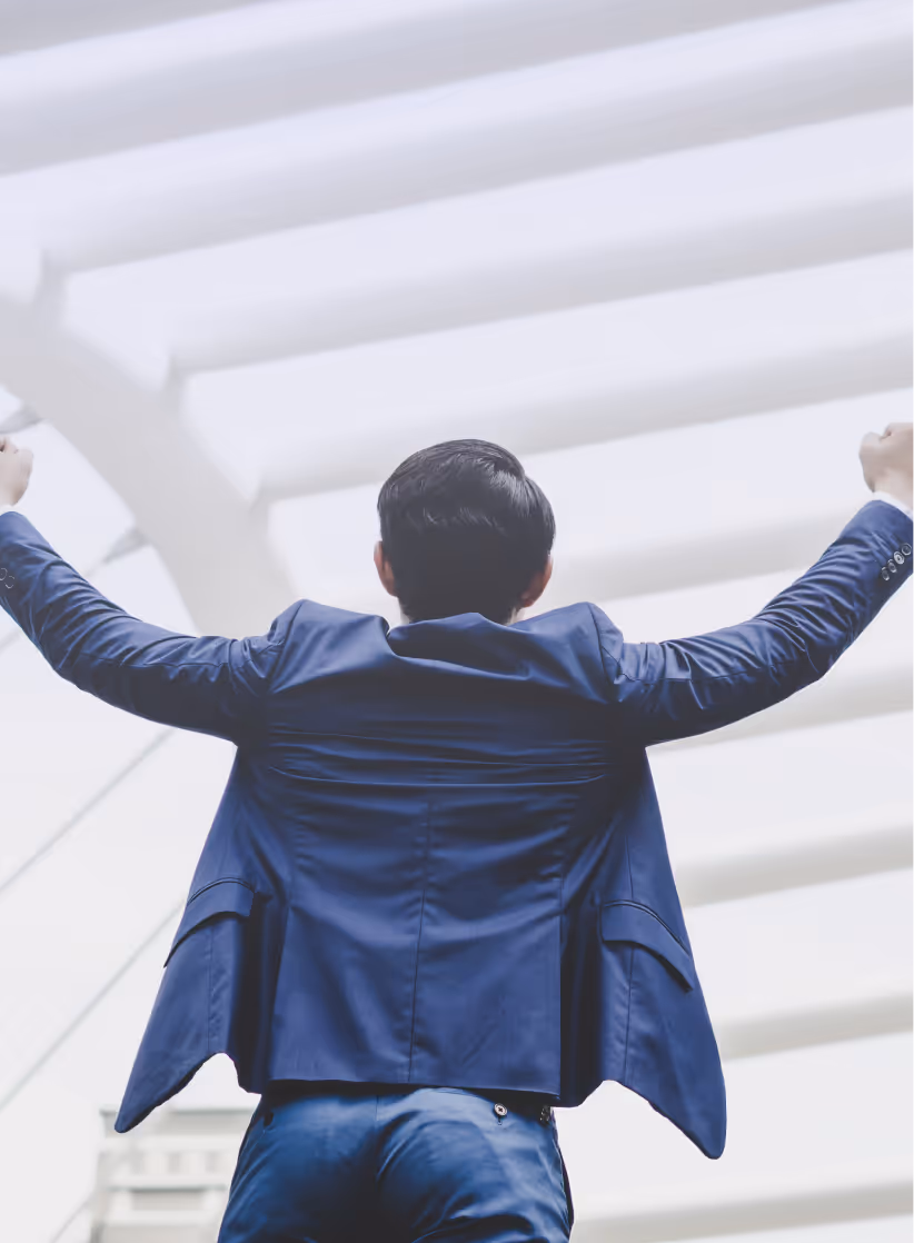 Person im Businessanzug mit ausgebreiteten Armen vor moderner Architektur – Symbolbild für Eigenverantwortung, Wachstum und Gestaltungsfreiheit bei MIND.