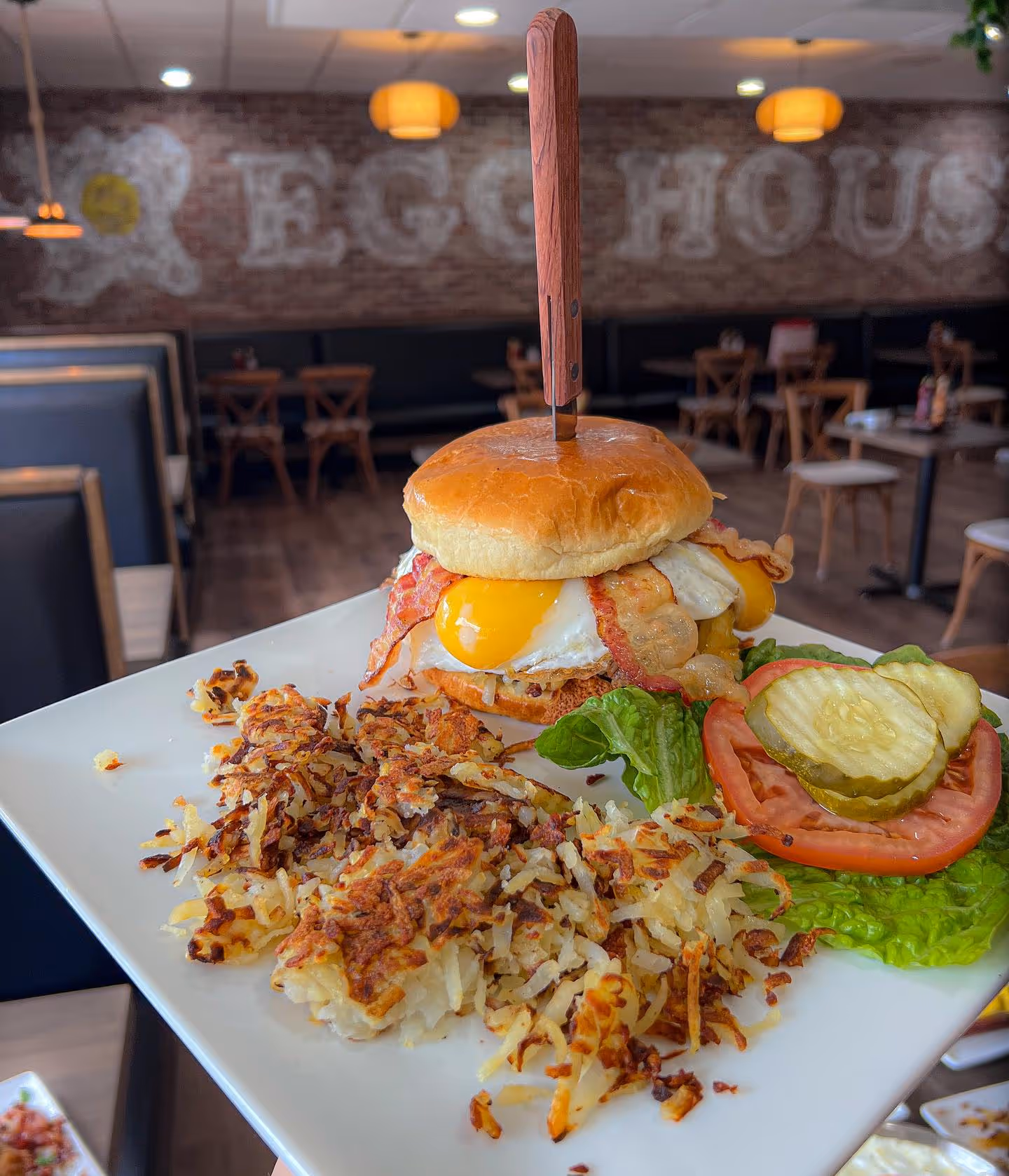 A plate of food with a sandwich and a pickle on a table.