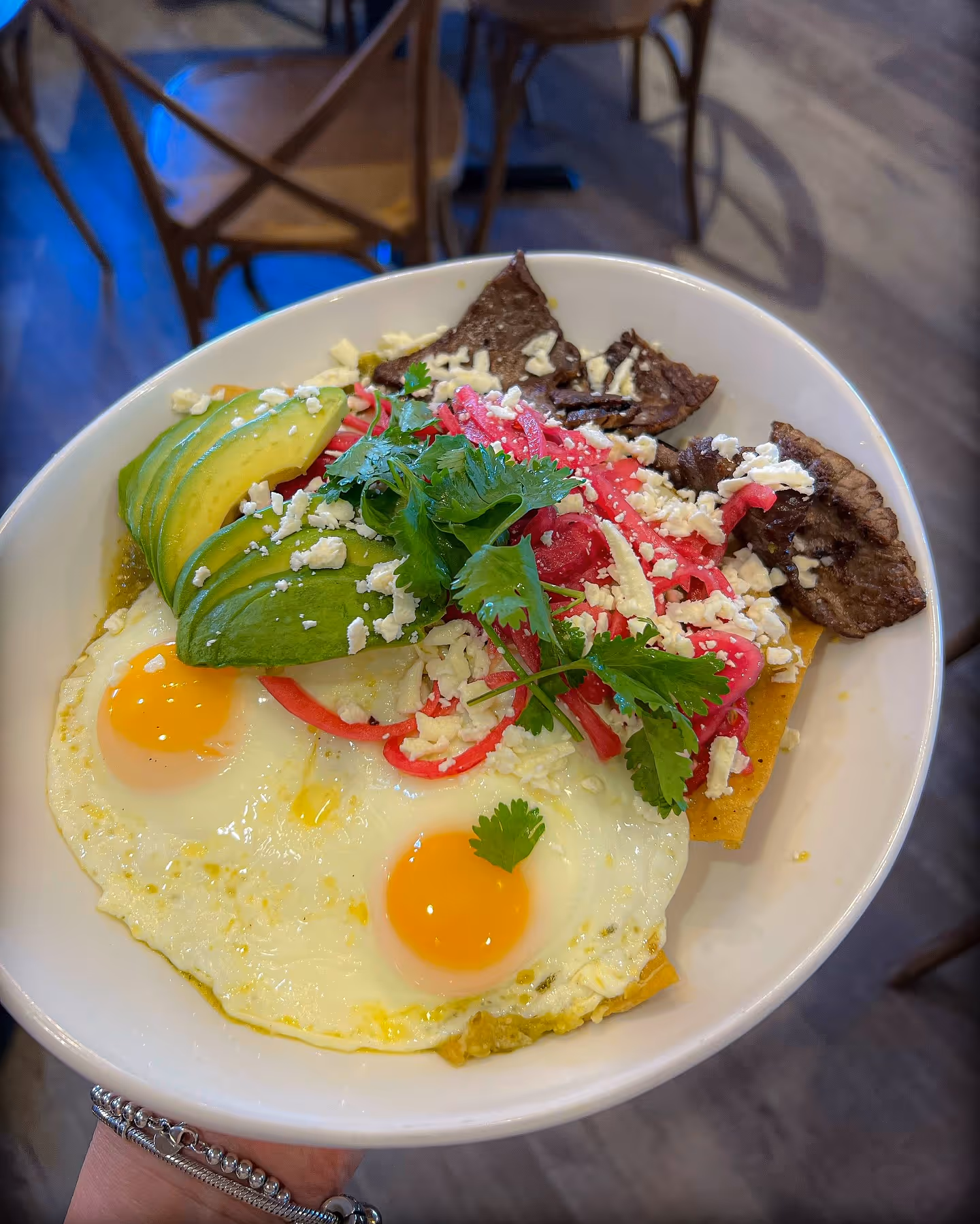 A white bowl filled with food and a person holding it.