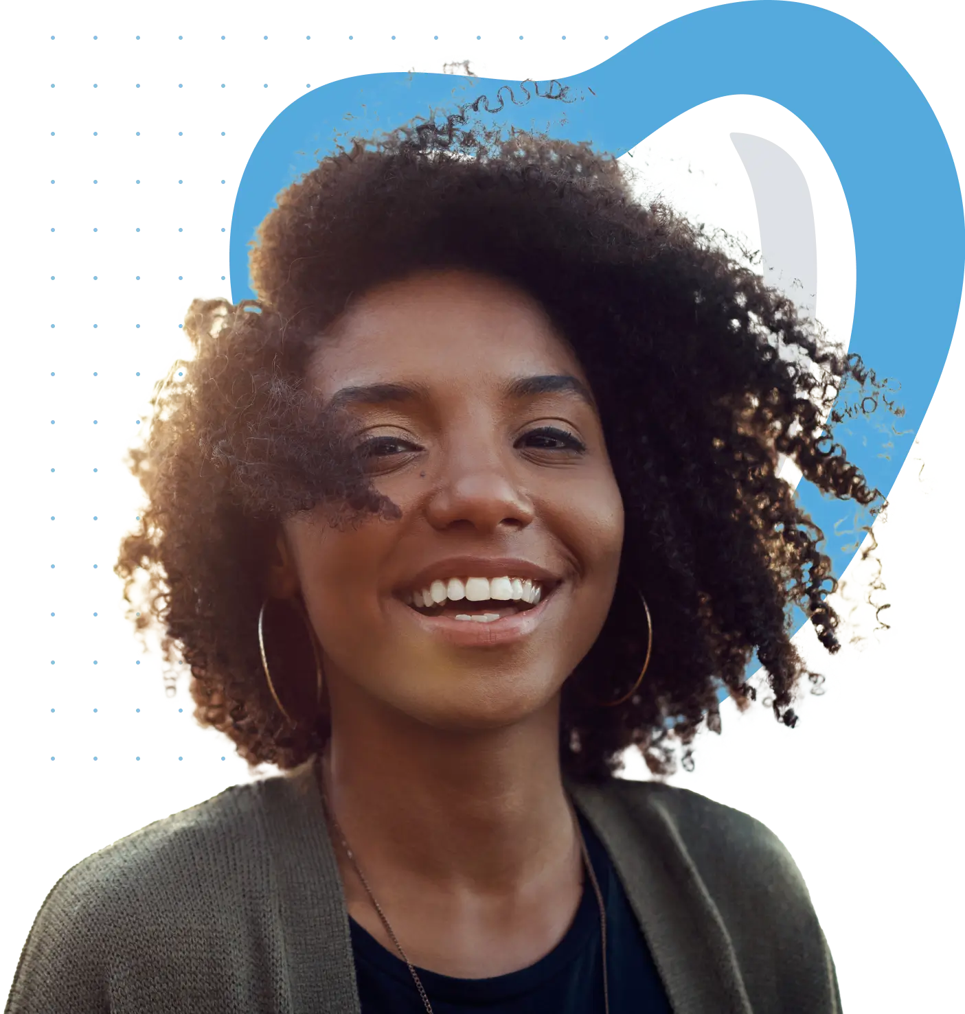 Smiling person with curly hair wearing hoop earrings and a cardigan, standing against a plain background.