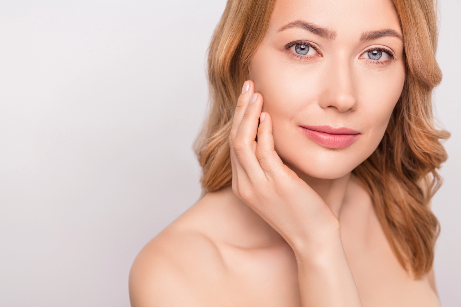 Young woman with a natural, glowing face showcasing aesthetic results from plastic surgery.