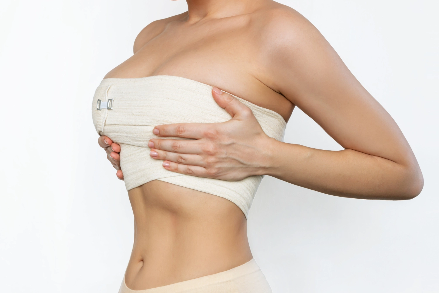A person's torso with a wide, elastic medical compression bandage wrapped around their chest, with their hands resting gently on it.