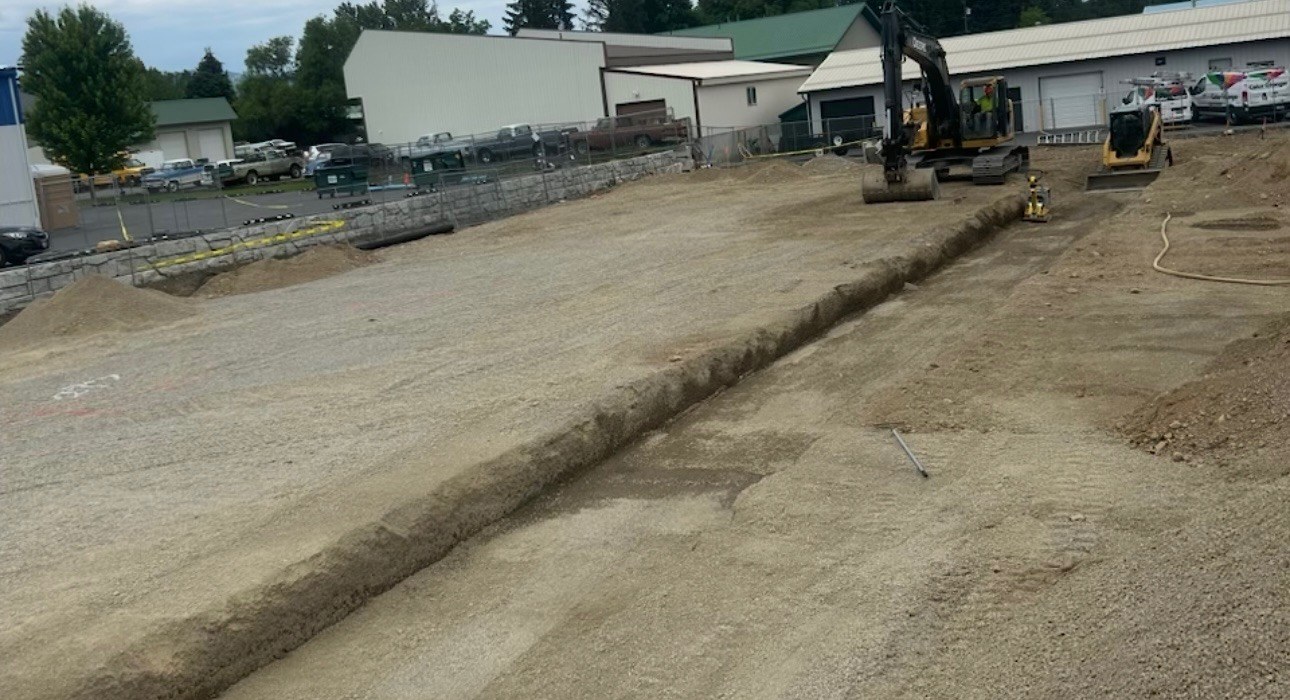 Excavator and long trench on a graded site in North Idaho