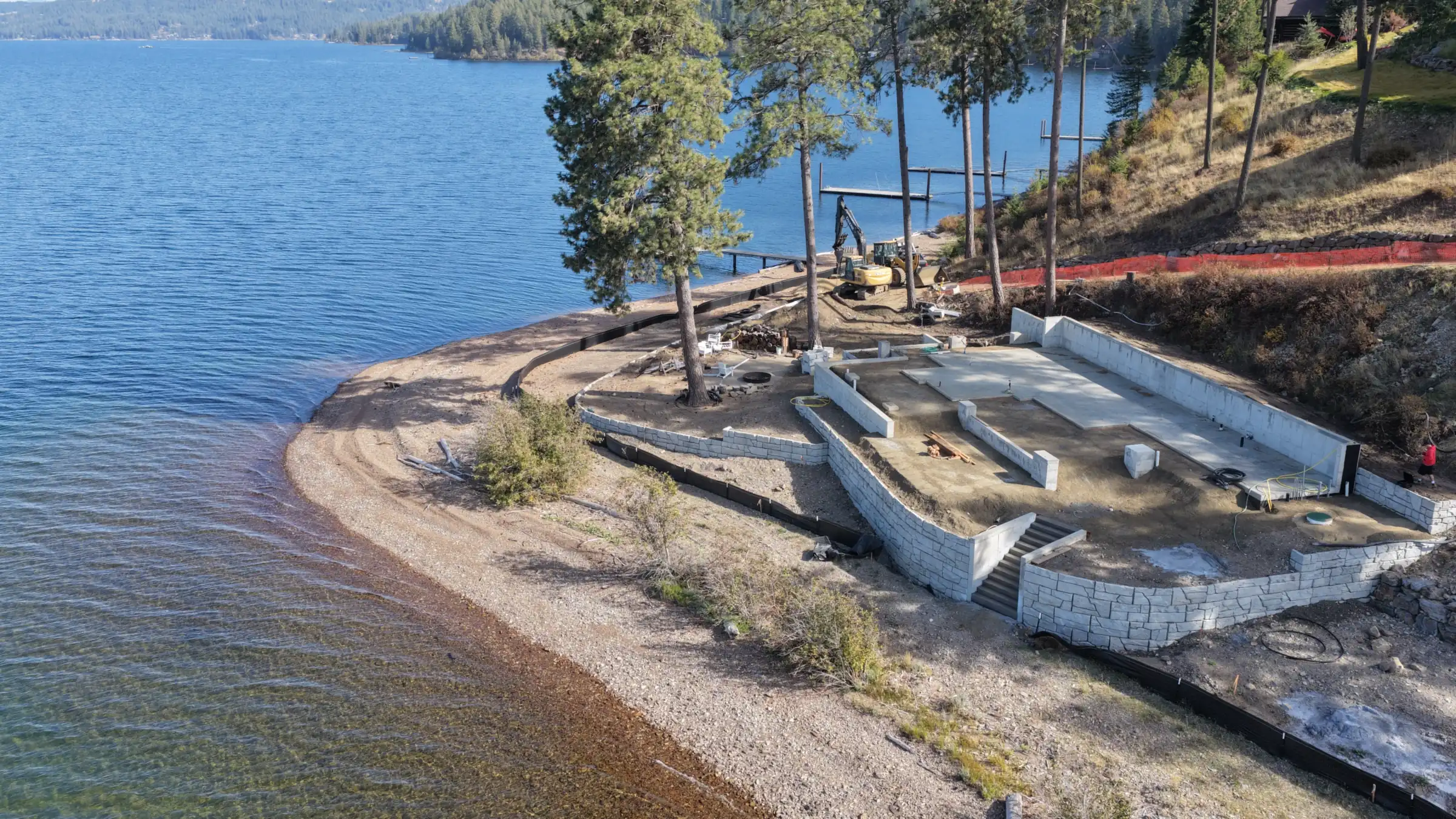 Aerial view of tiered block retaining walls built by IVR Earthworks on a lakefront home site in North Idaho