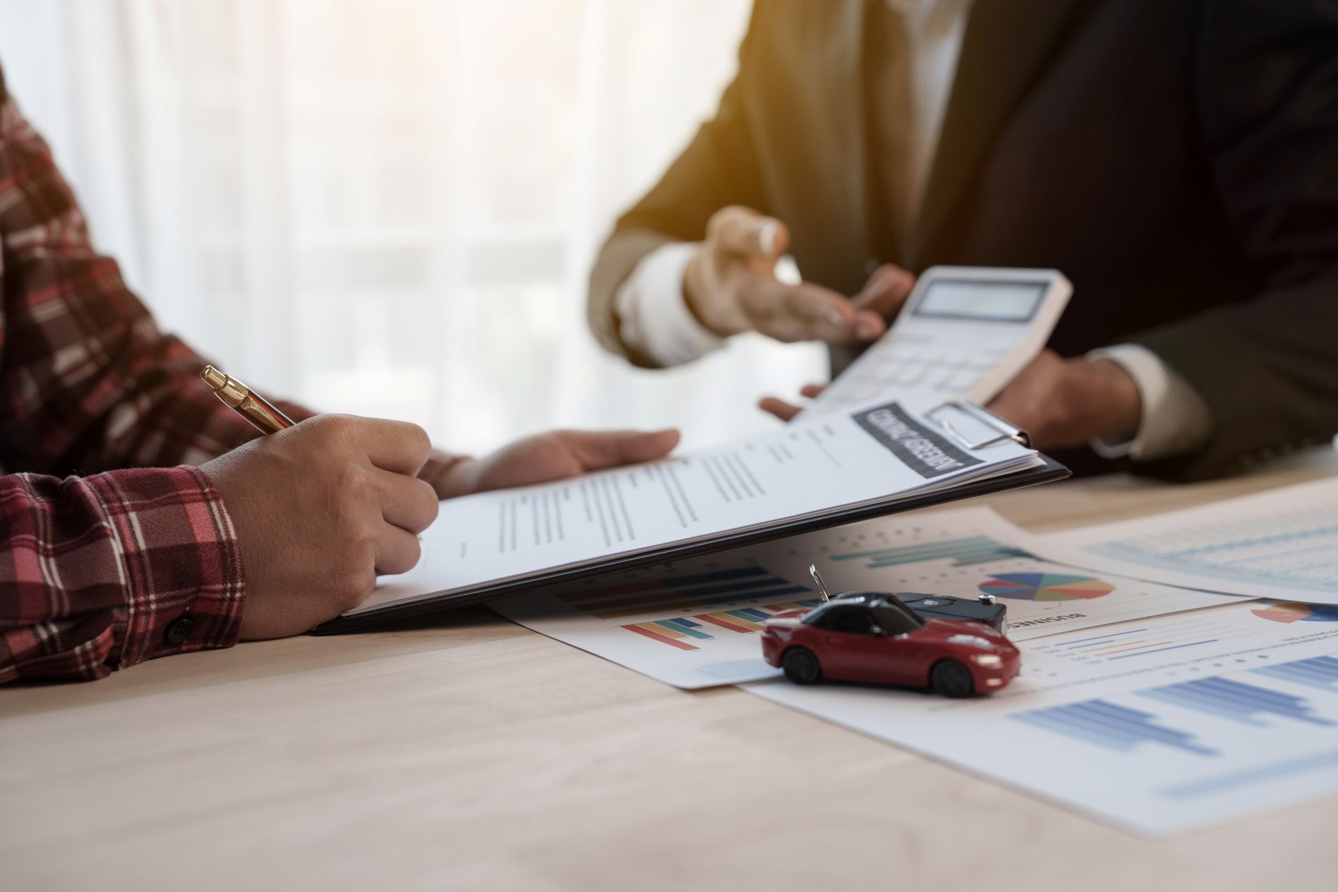Person signing document with toy car next to clipboard