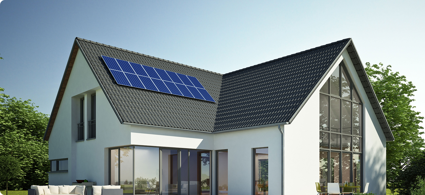 Modern white house with large windows and solar panels on a dark tiled roof, surrounded by green trees.
