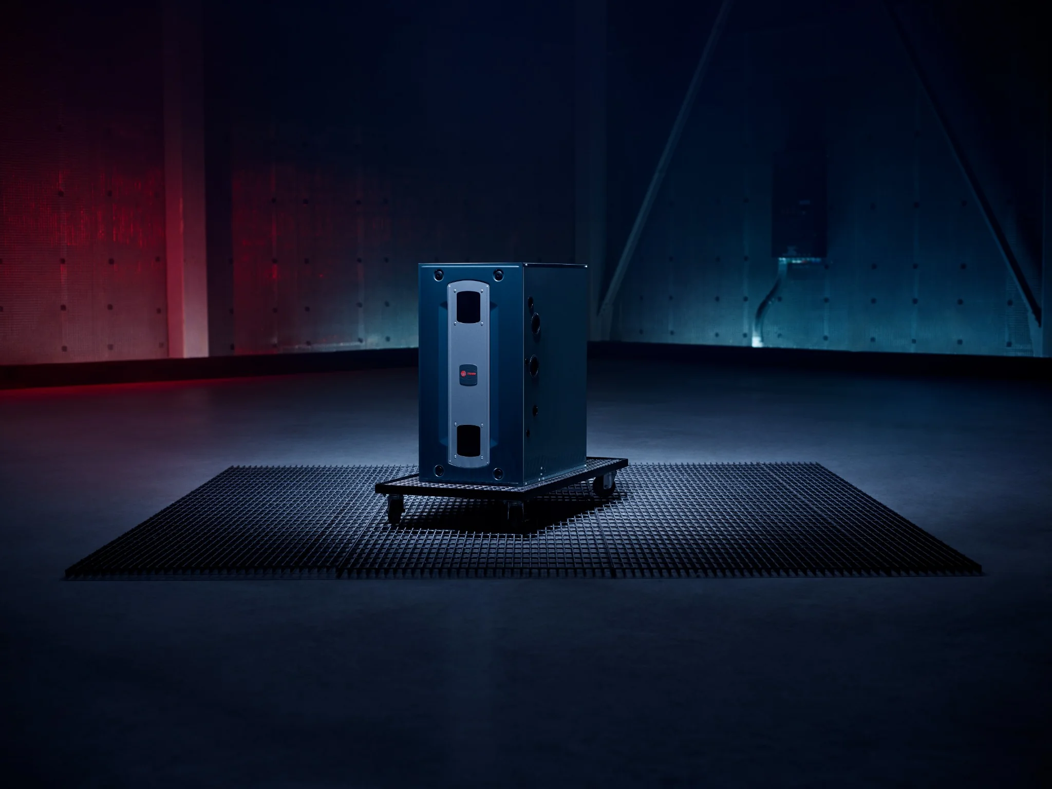 Industrial furnace unit placed on a wheeled platform in a dimly lit room with red and blue lighting.