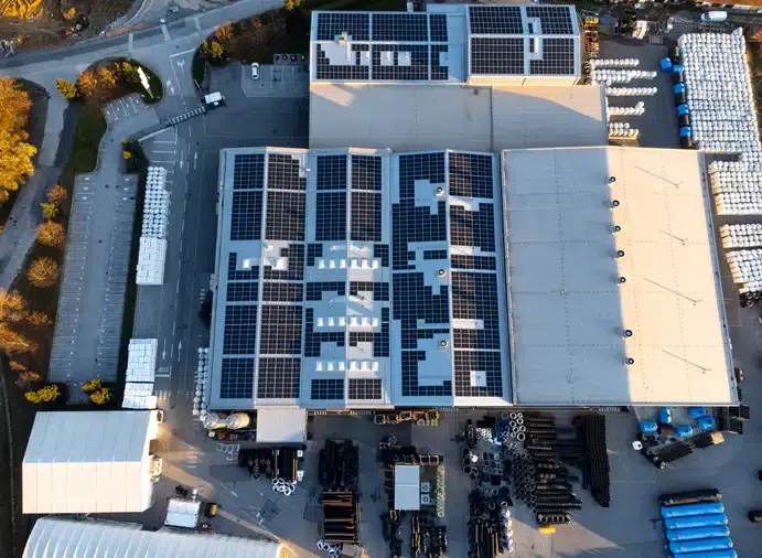 Aerial view of a commercial building with solar panels on the roof, surrounded by storage areas, showcasing solar energy solutions for sustainable power generation.